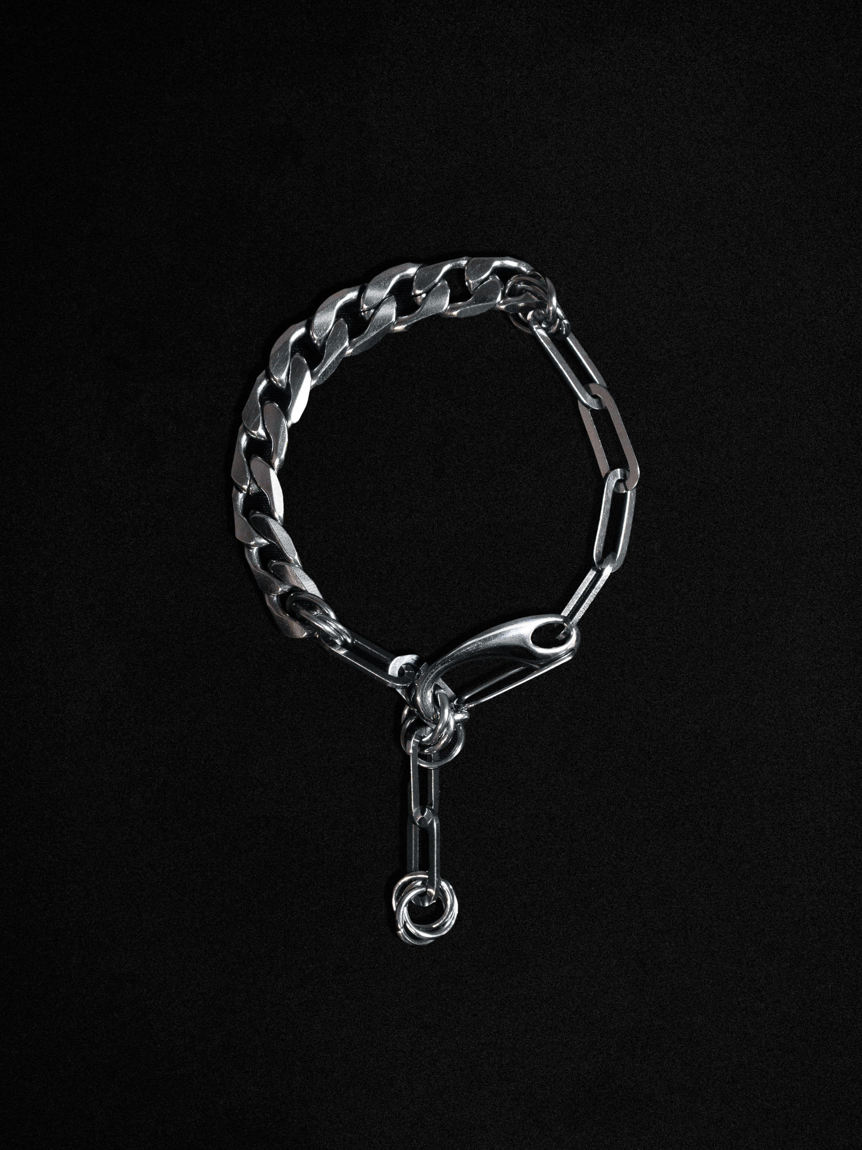 A silver-colored chunky bracelet with Cuban chain design and hardware details on a black background.