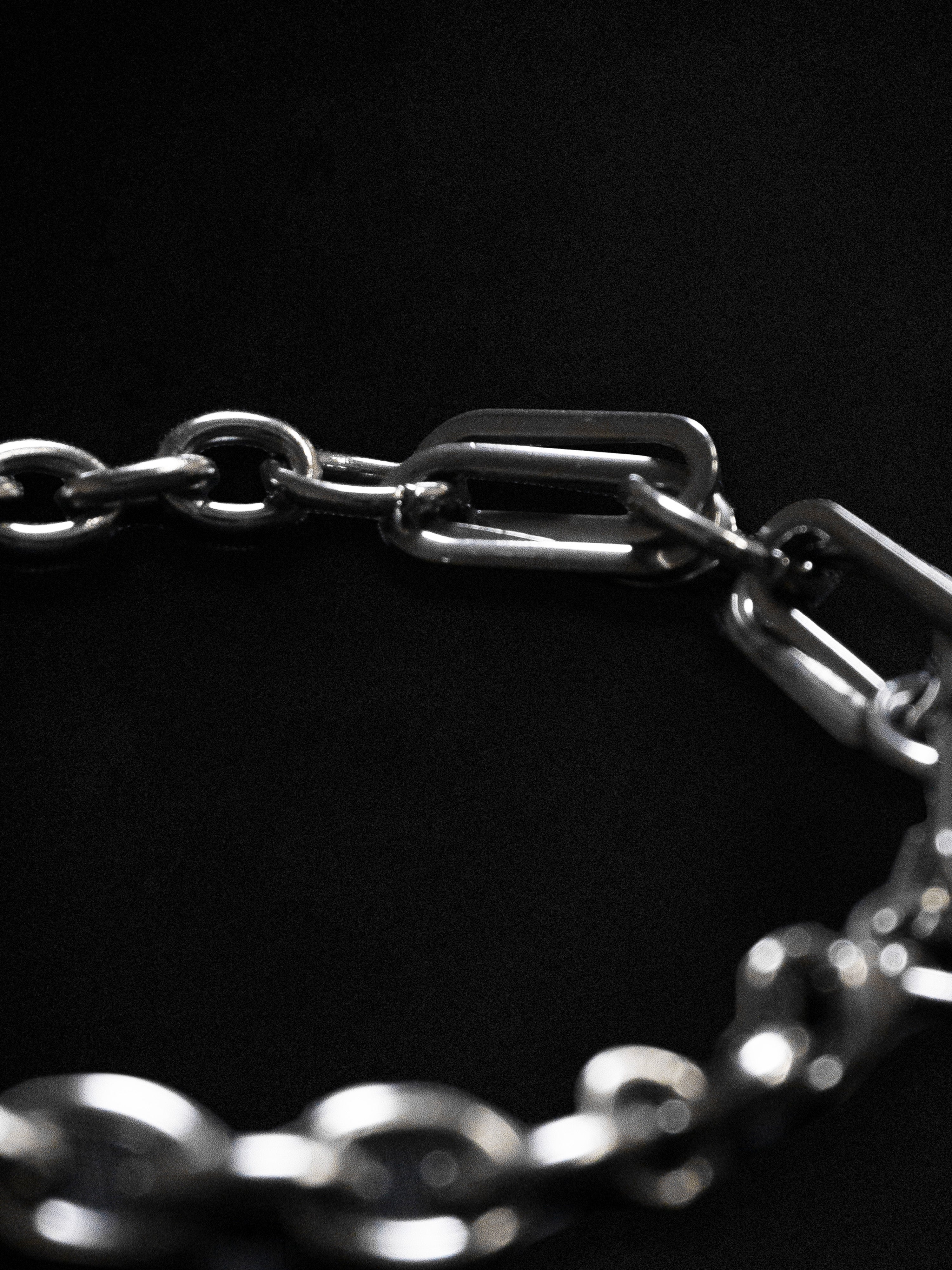 Close up of a silver chain bracelet with clip design on a black background 