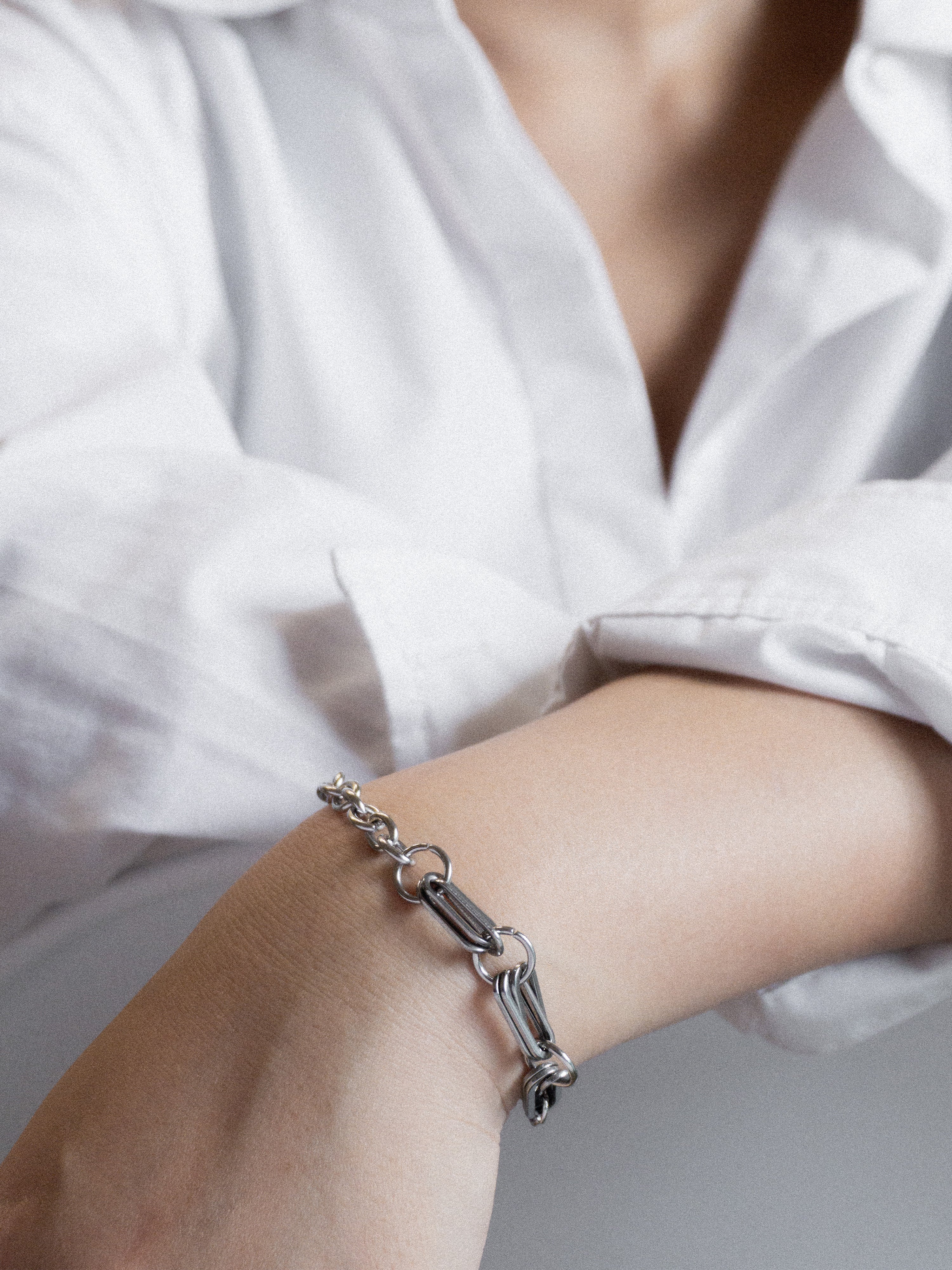 Silver bracelet on a wrist with a blurred white shirt background