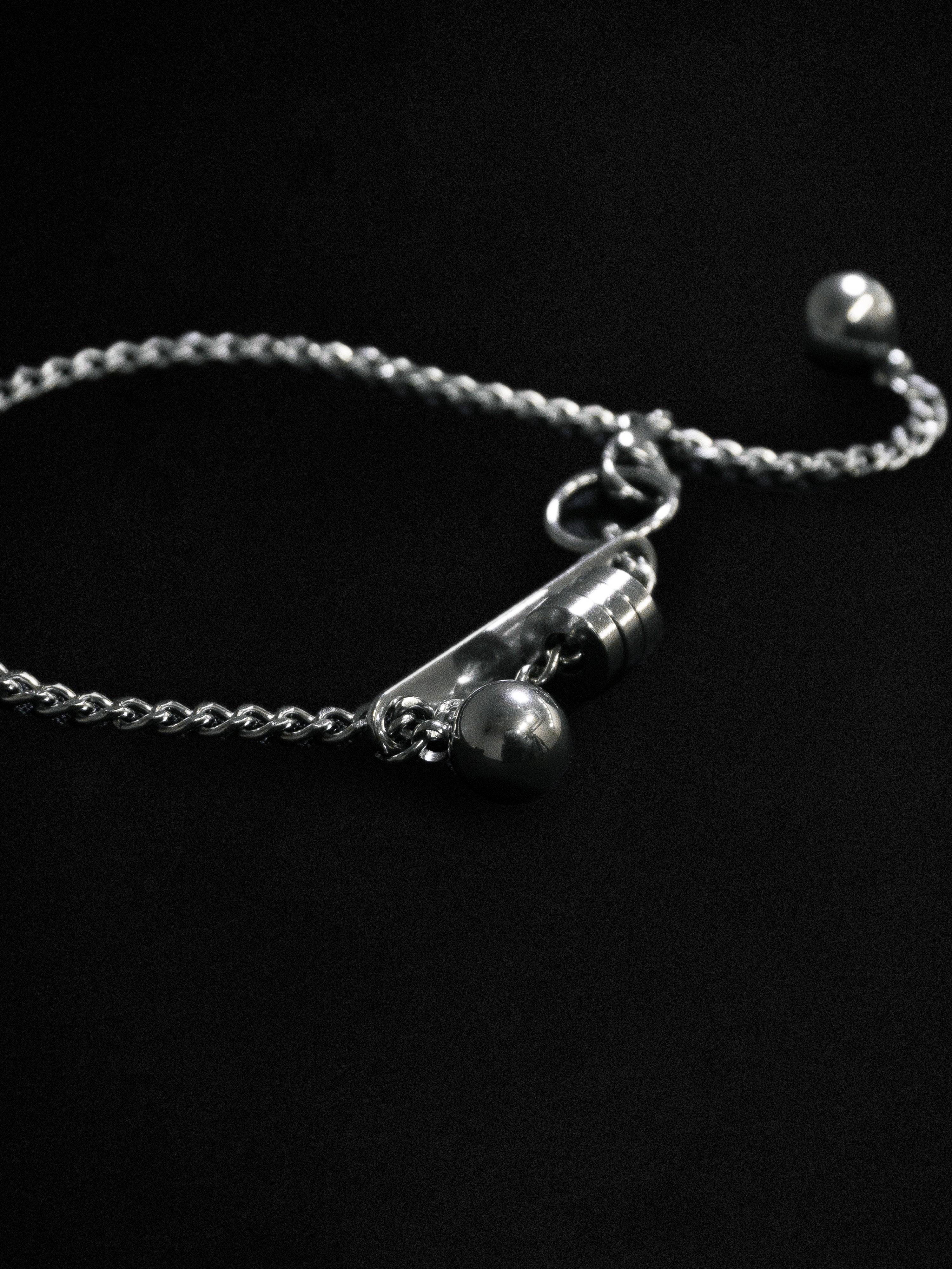 Close up of a silver chain bracelet on a black background 