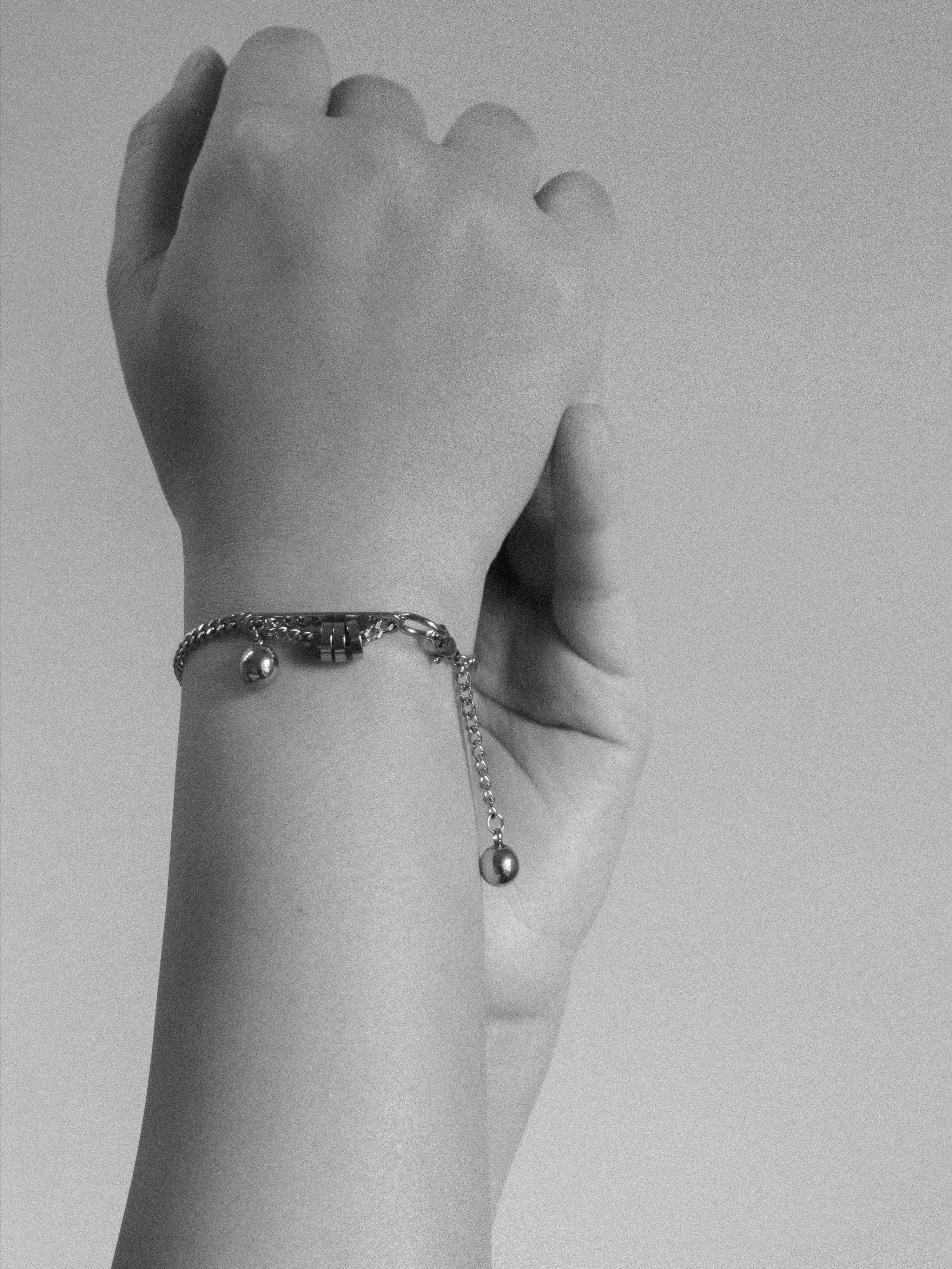 Hand wearing a bracelet on a plain background