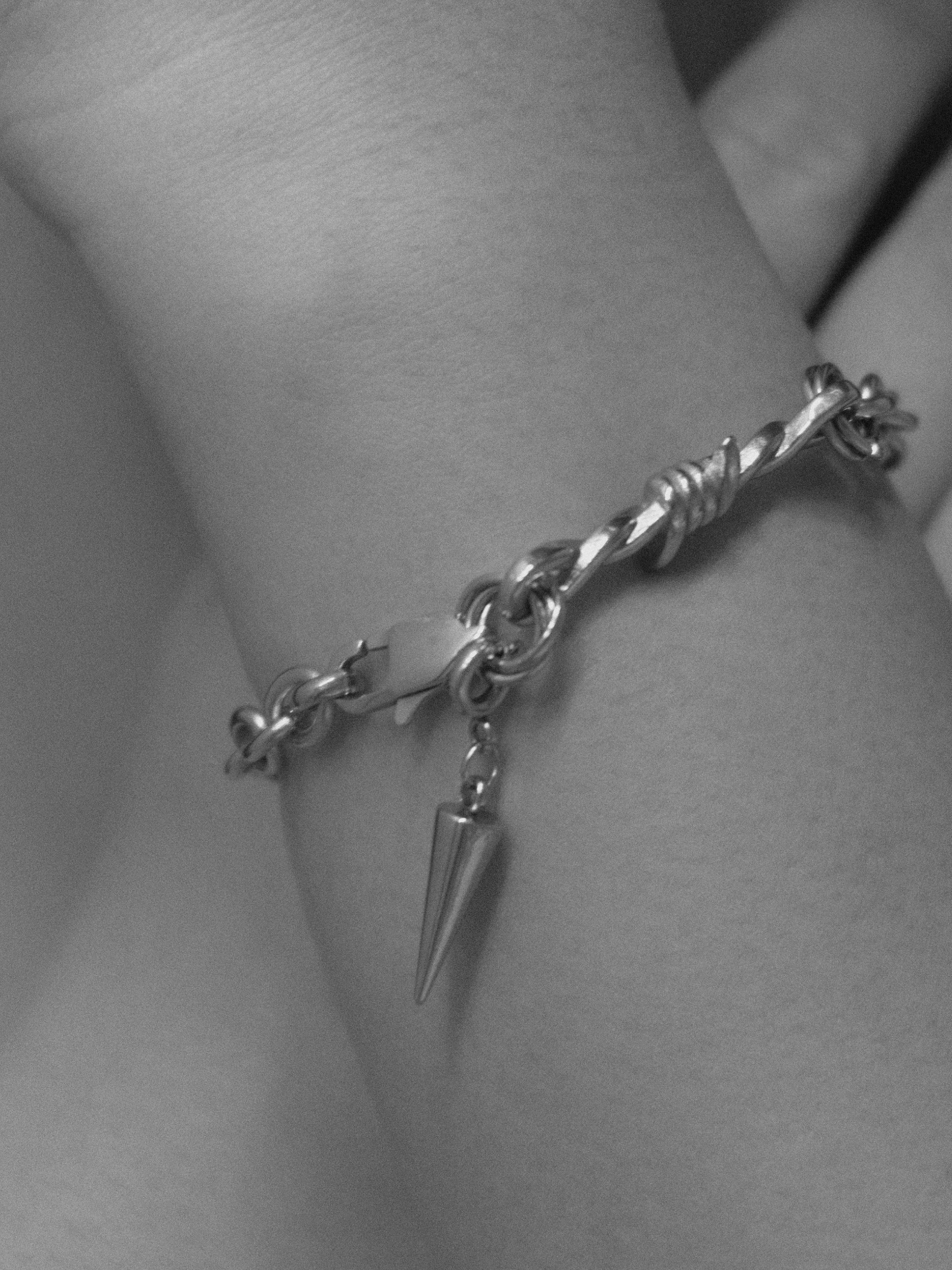 Silver bracelet with a pine cone charm on a wrist