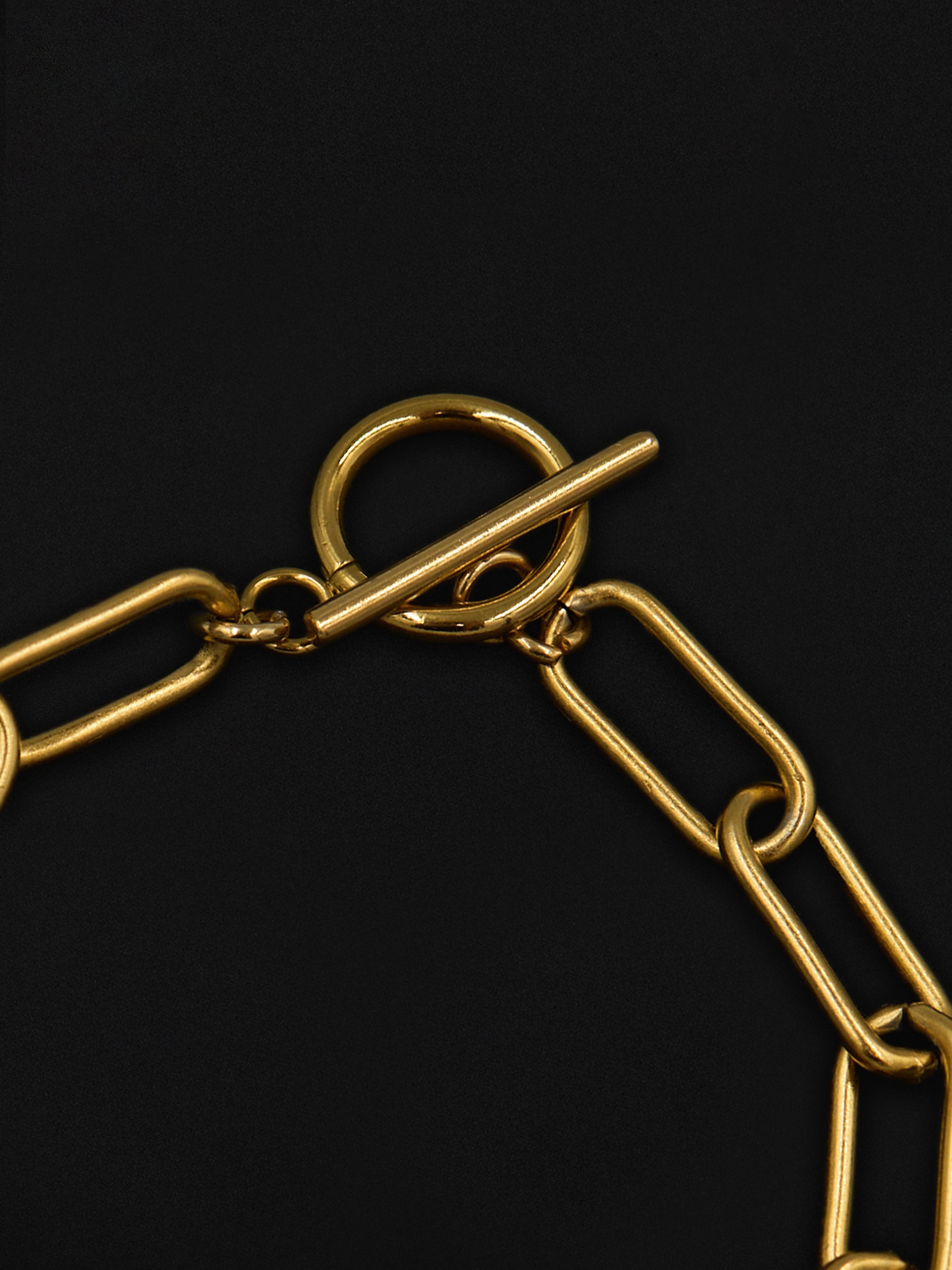 Close up of a clasp on a gold chain bracelet on a black background