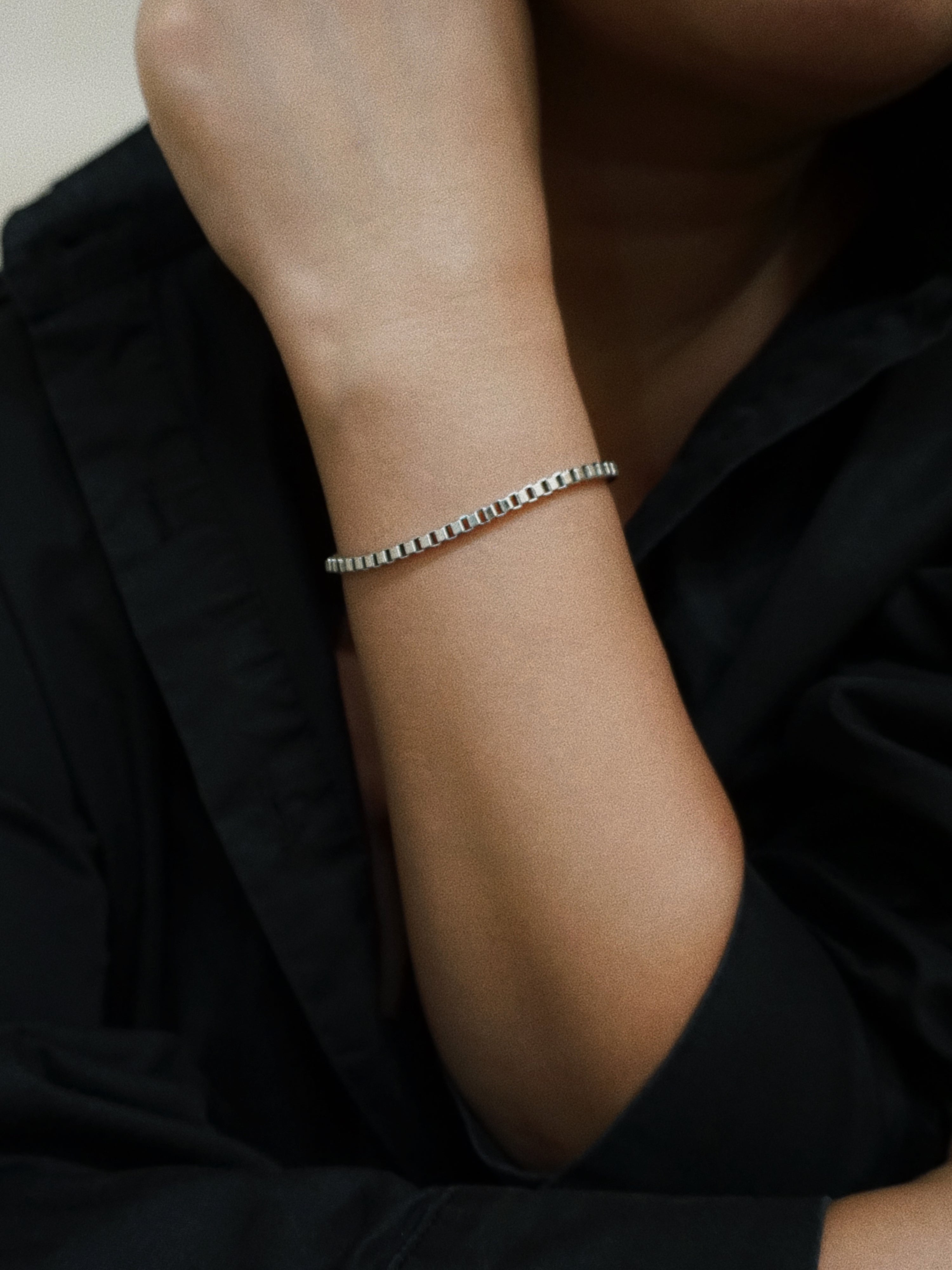Silver bracelet on a person's wrist with a black background