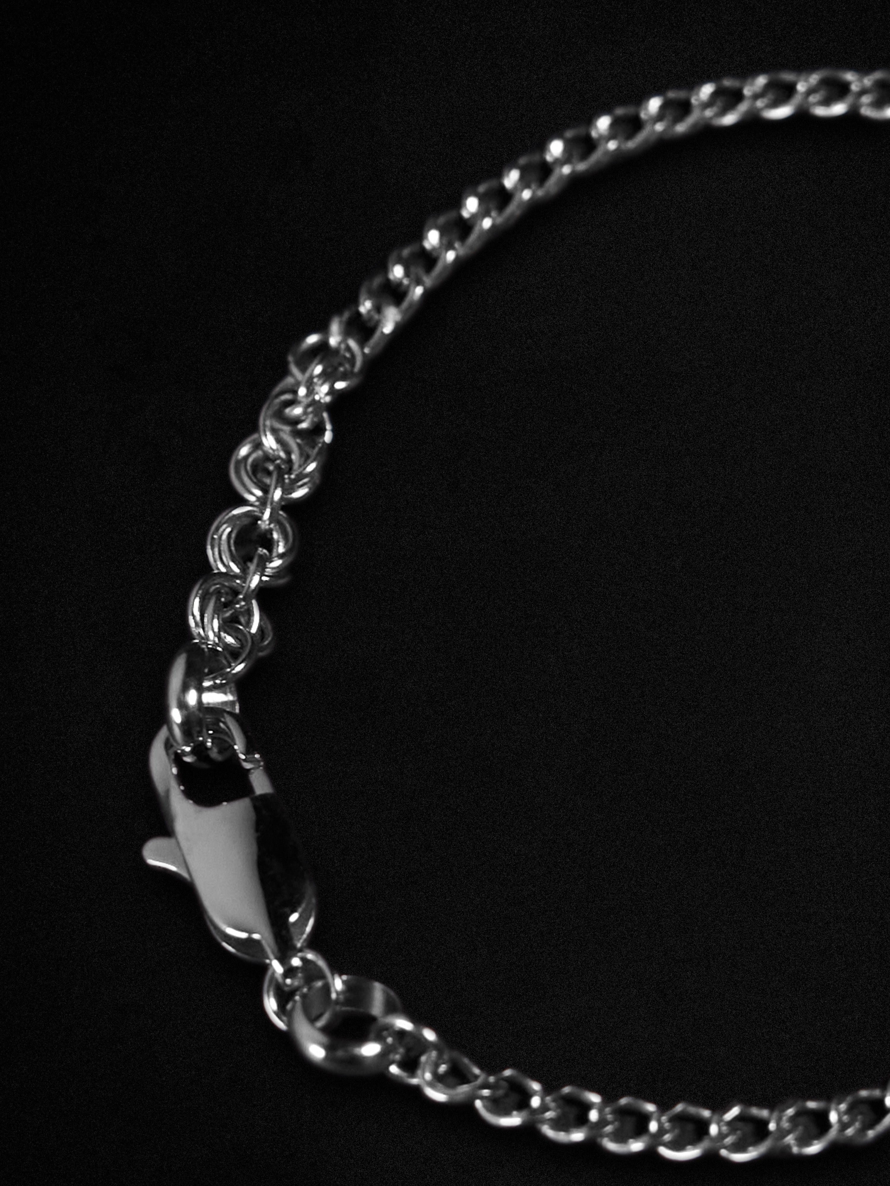 Silver chain bracelet with a clasp on a black background