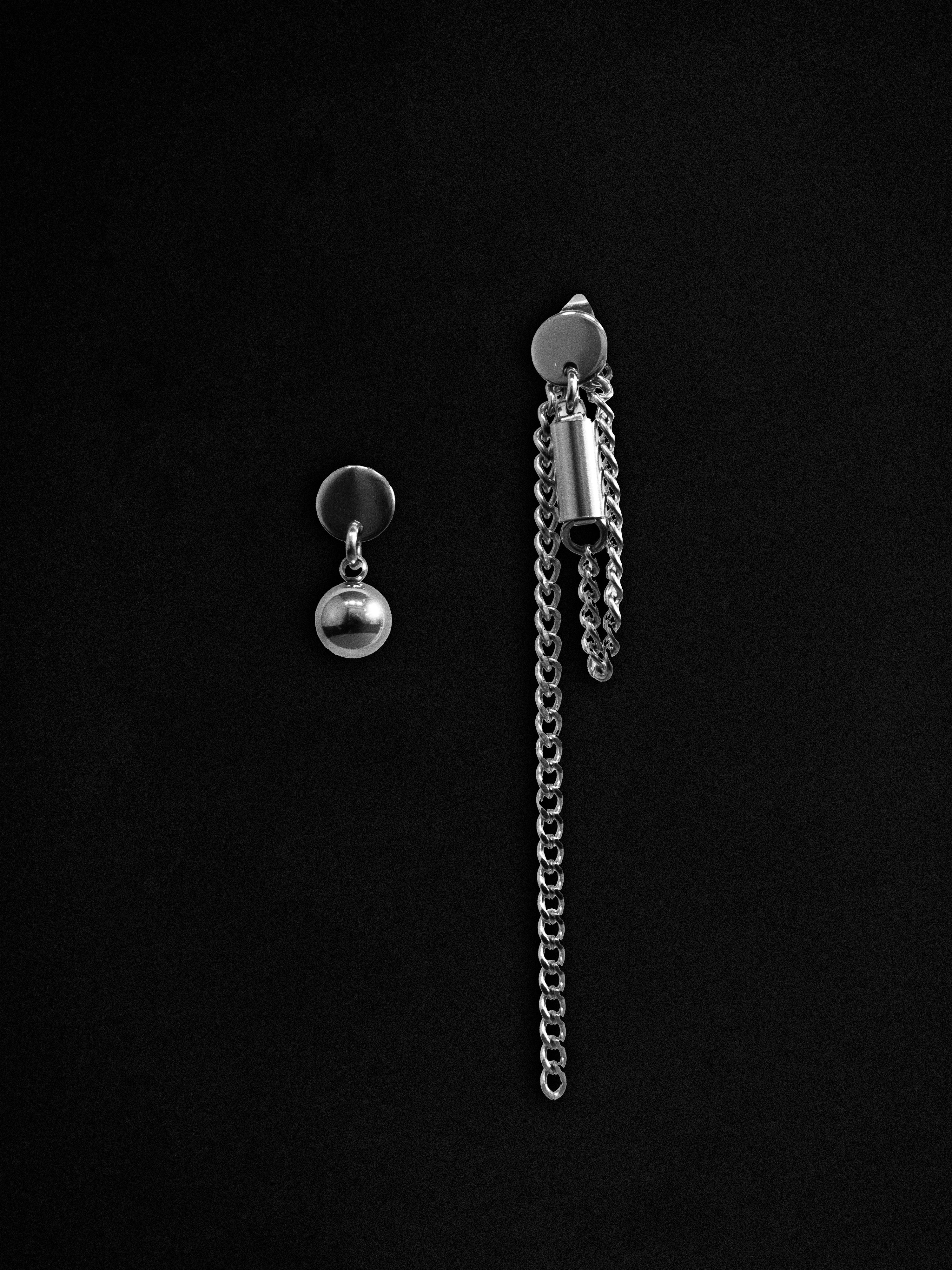 Silver chain earring with a spherical pendant on a black background