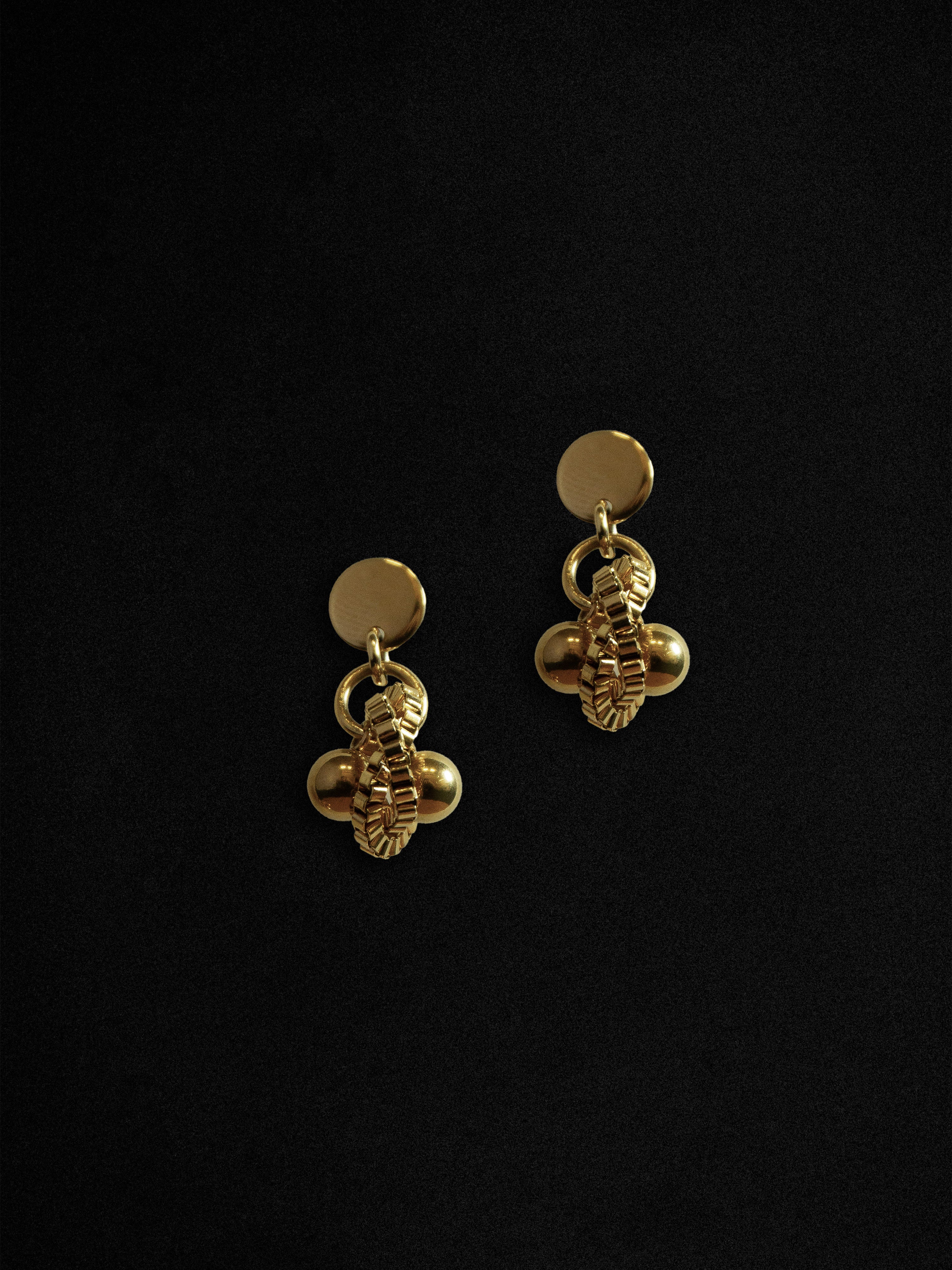 Gold bee-shaped earrings on a black background
