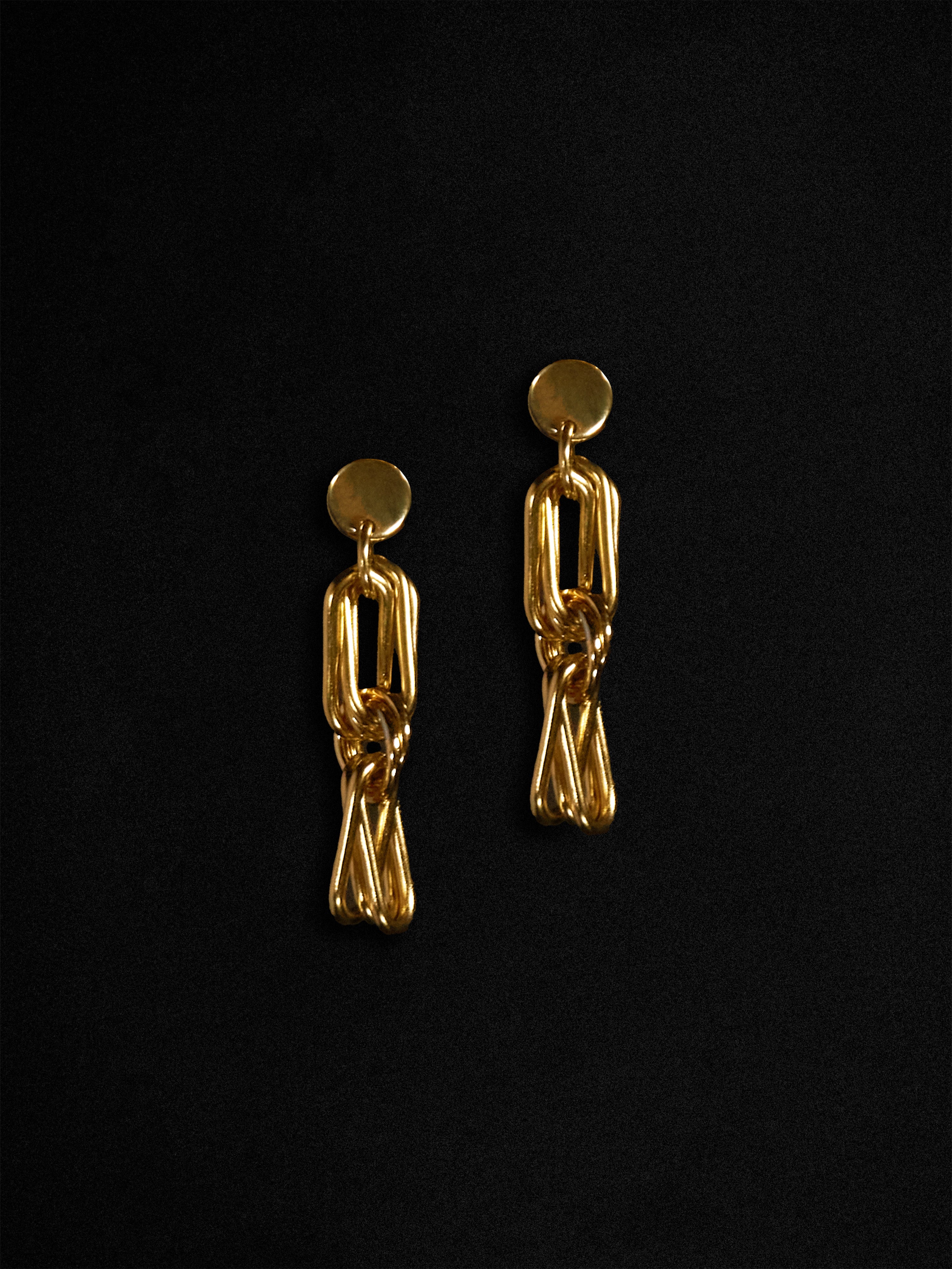 Gold stack clip chain earrings on a black background