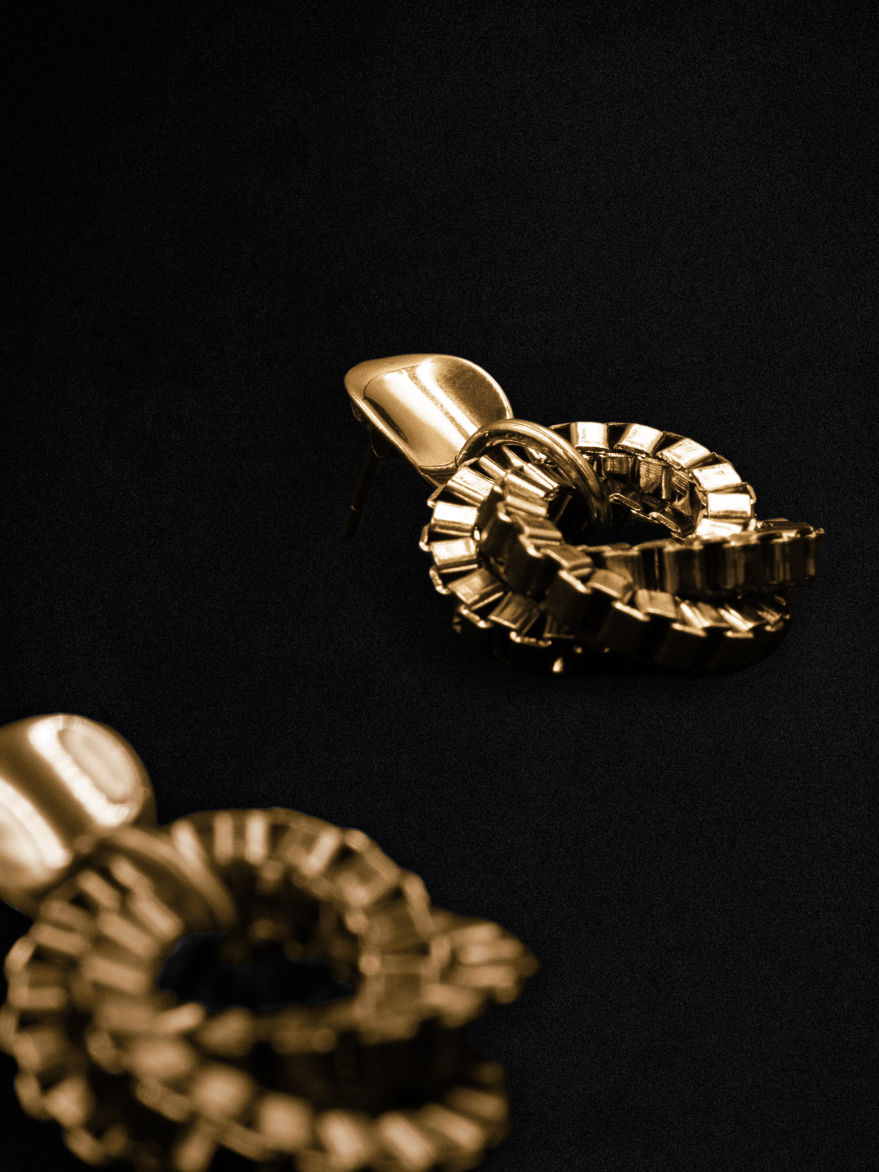 Gold earrings with a unique design on a black background