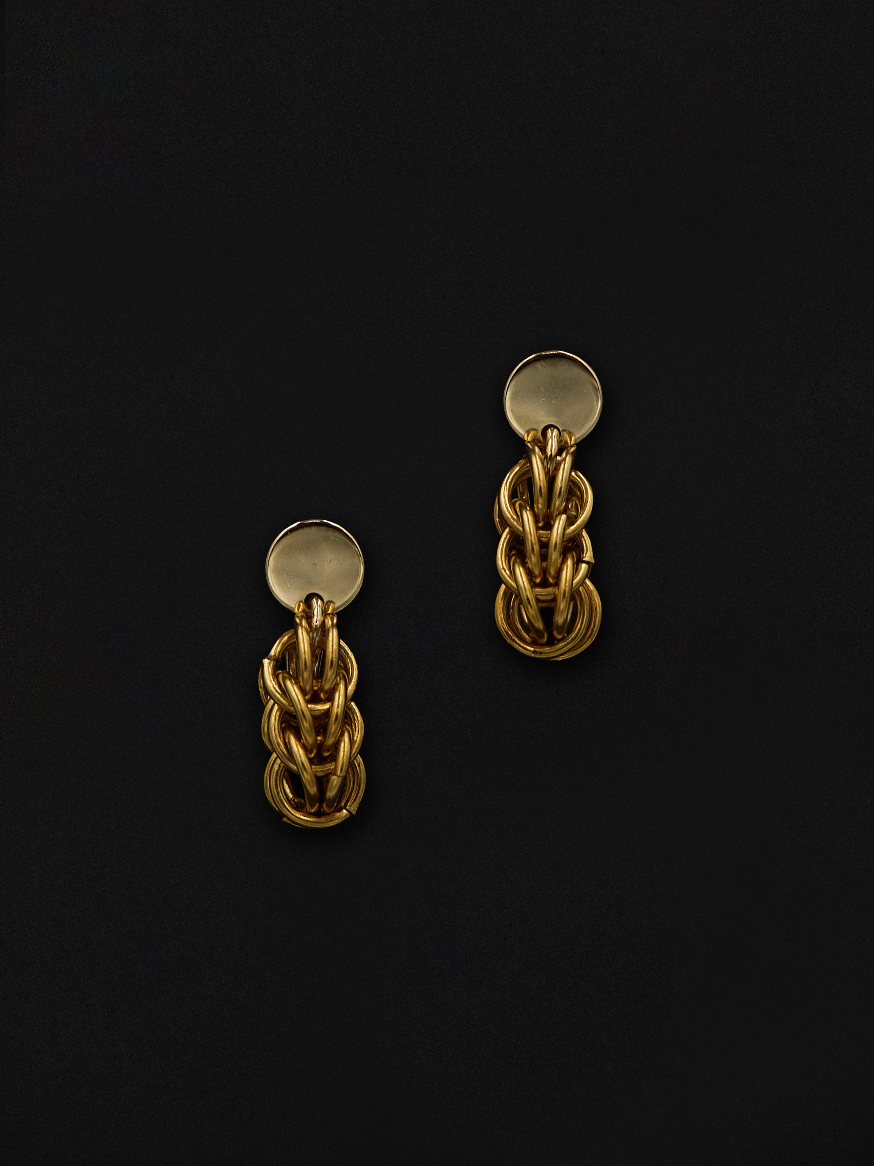 Pair of gold chain earrings on a black background