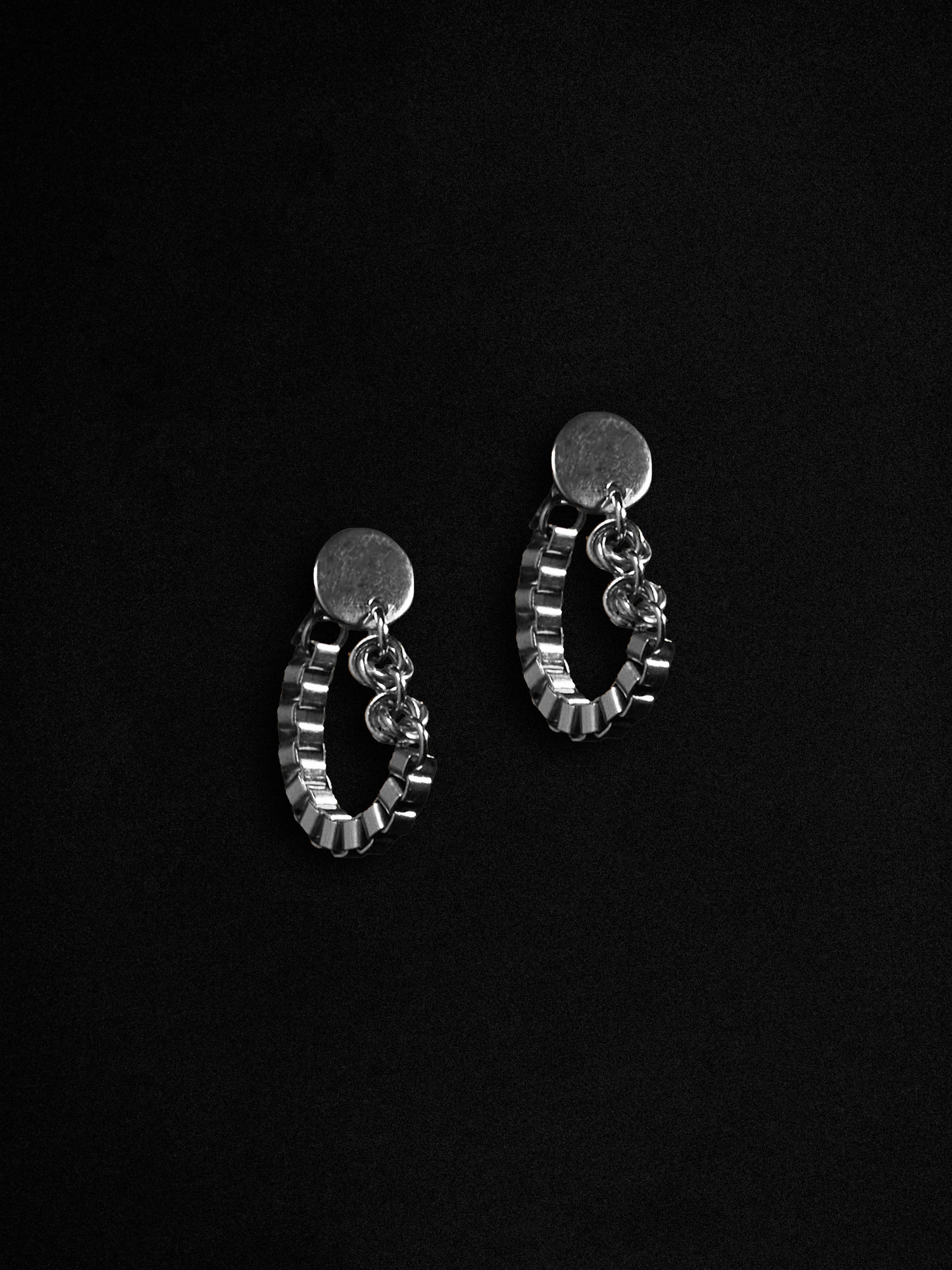 Pair of silver hoop earrings on a black background