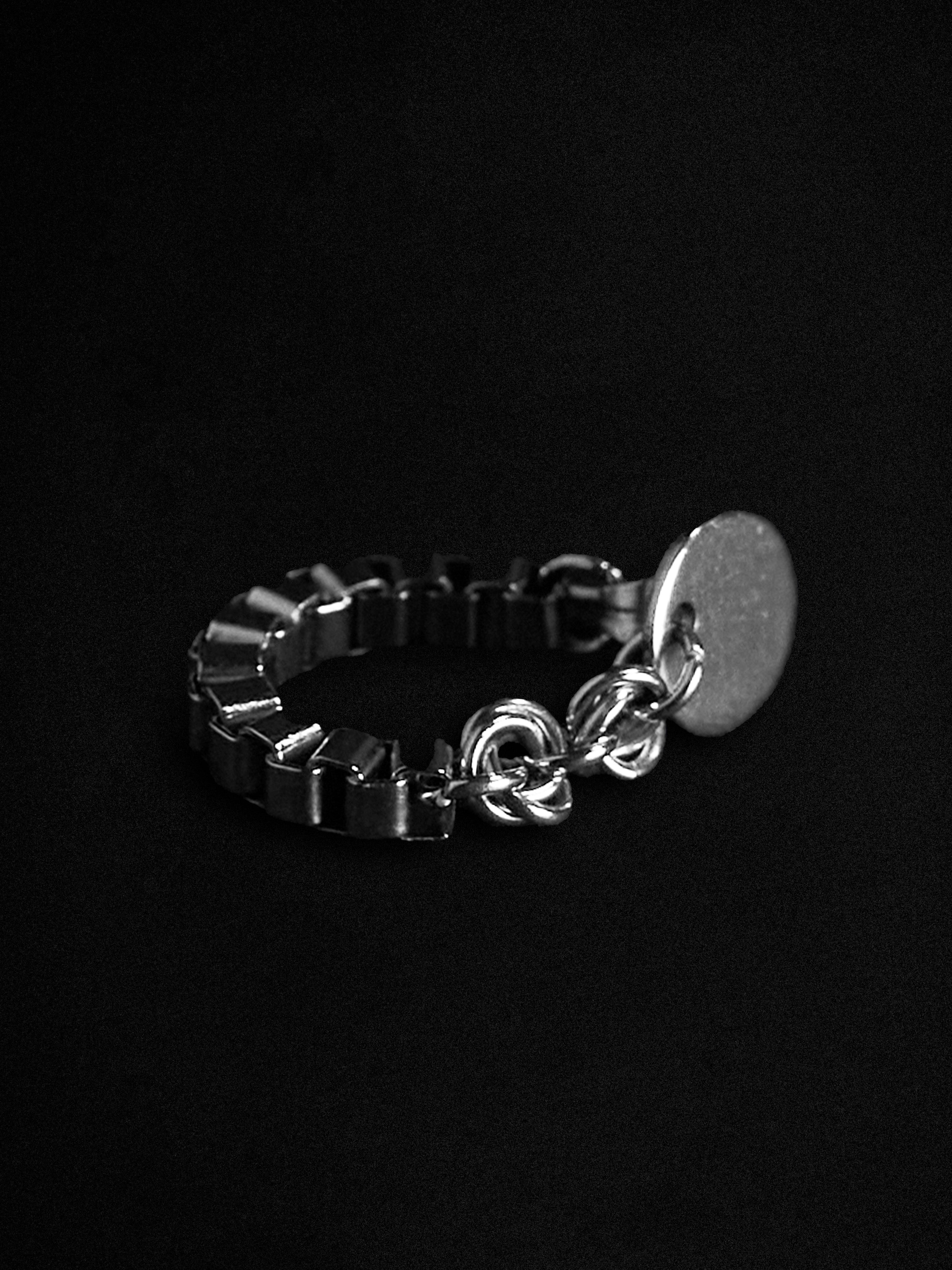 Silver chain earrings with a circular stud on a black background