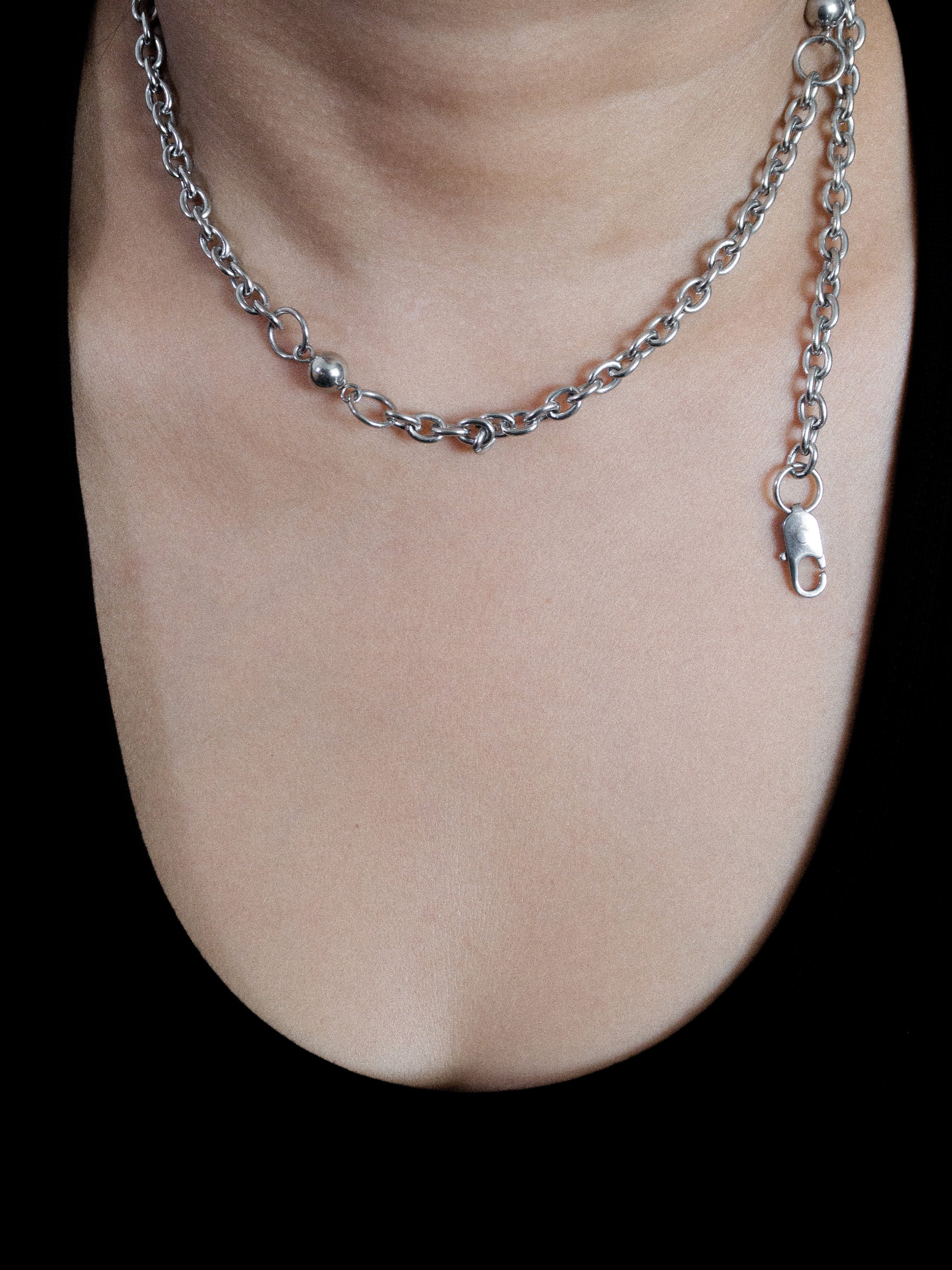 Silver chain necklace on a person's neck wearing a black top