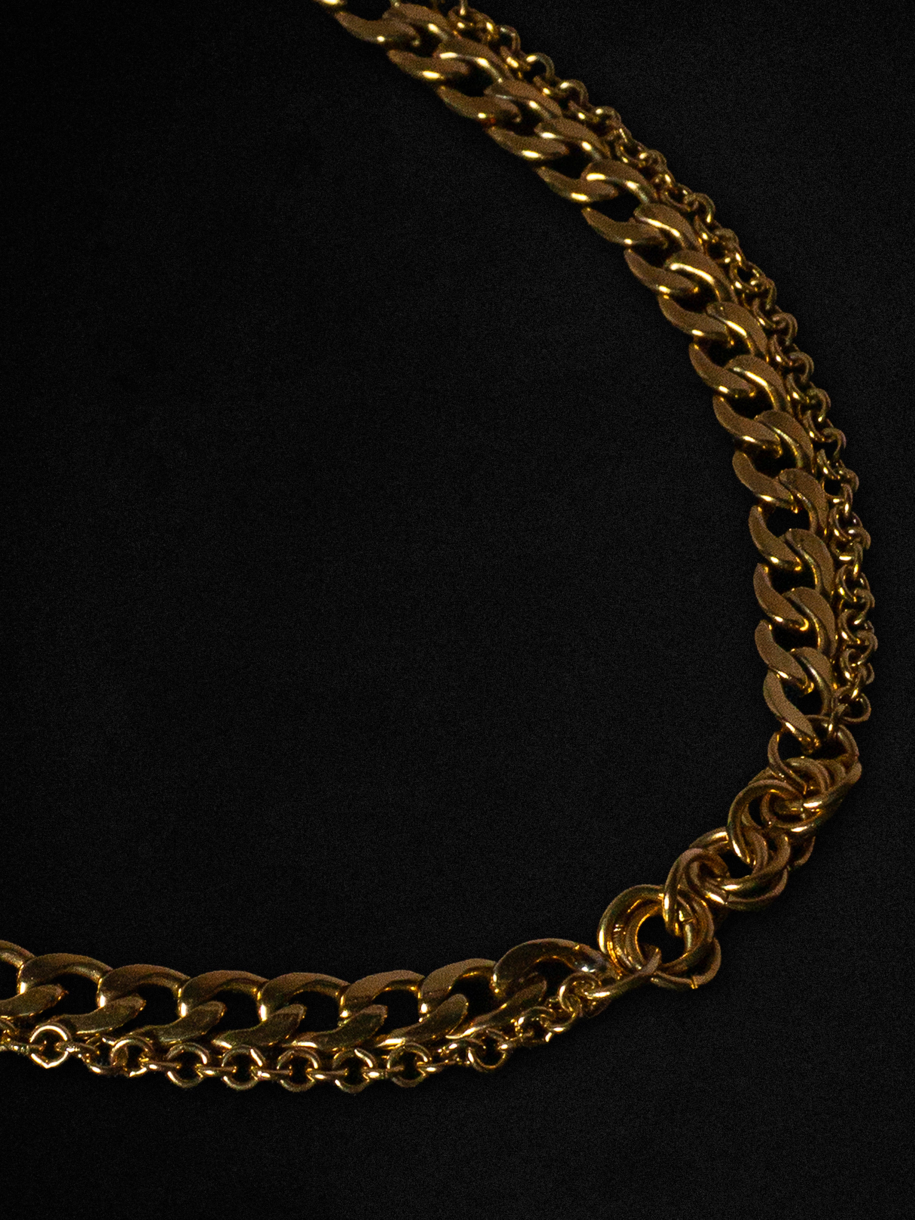 Closes up of a gold chain necklace on a black background