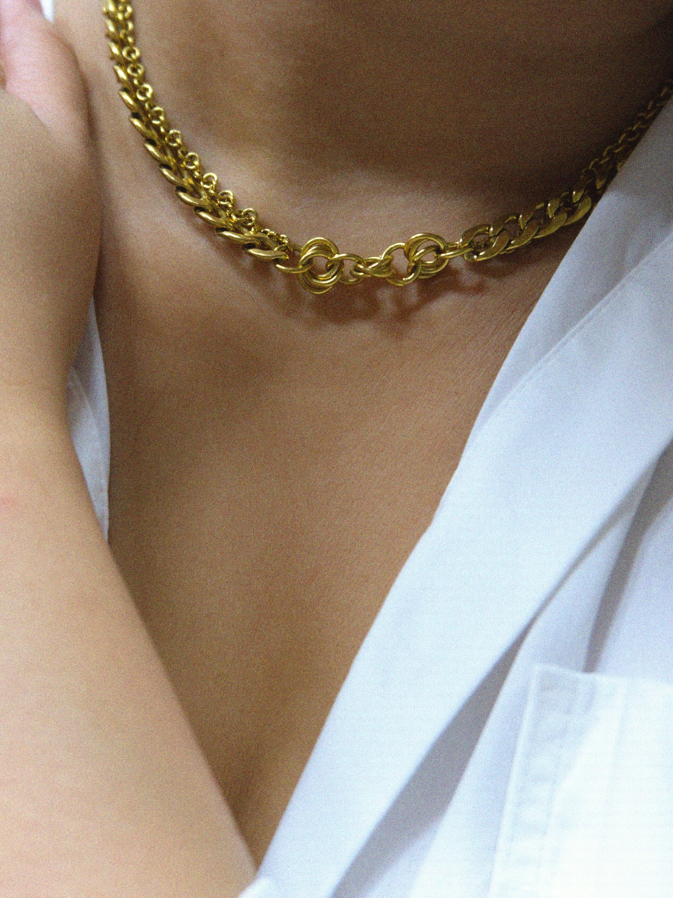 Gold chain necklace worn by a person with a white shirt