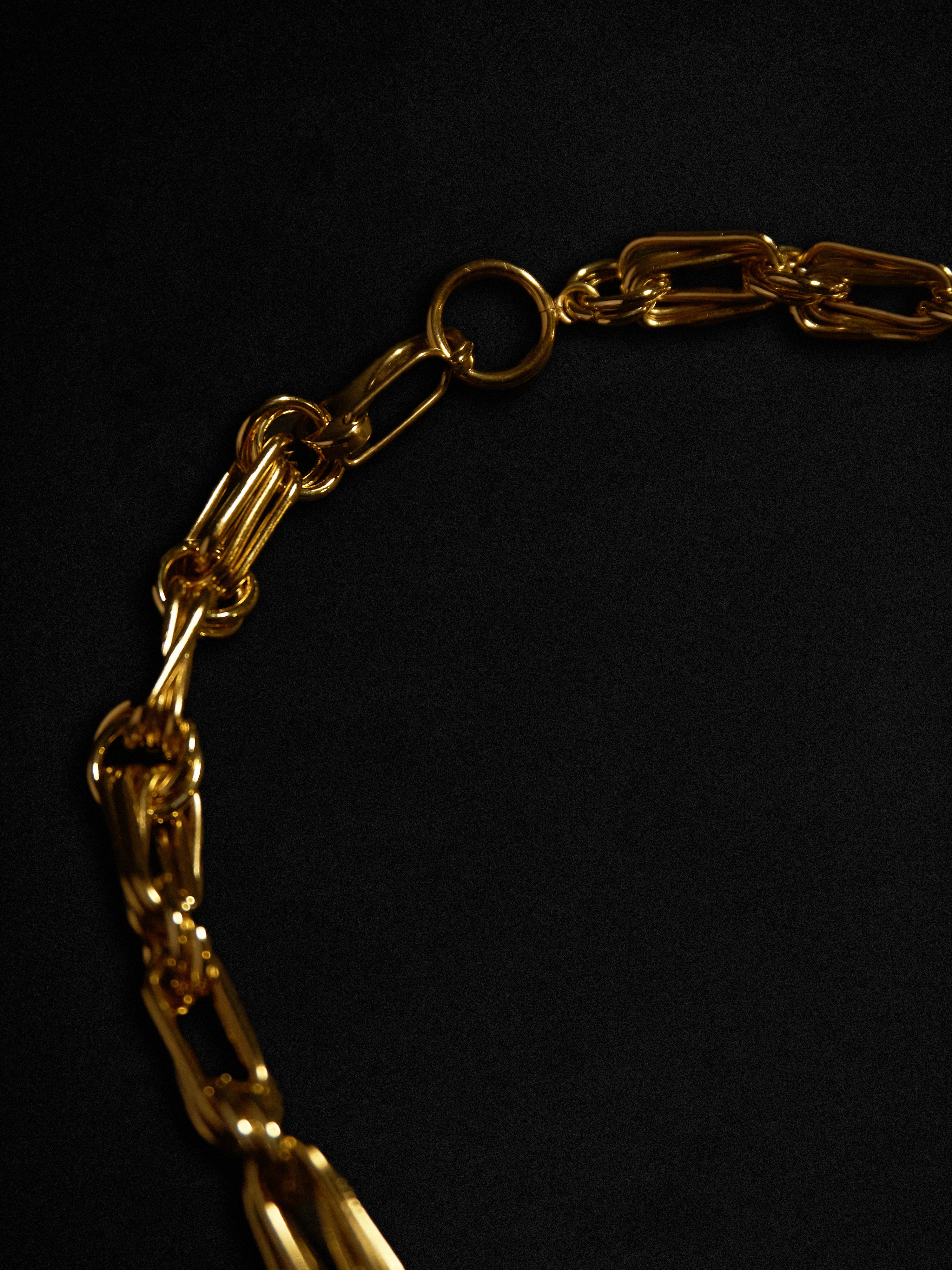 Close-up of a gold chain necklace on a black background
