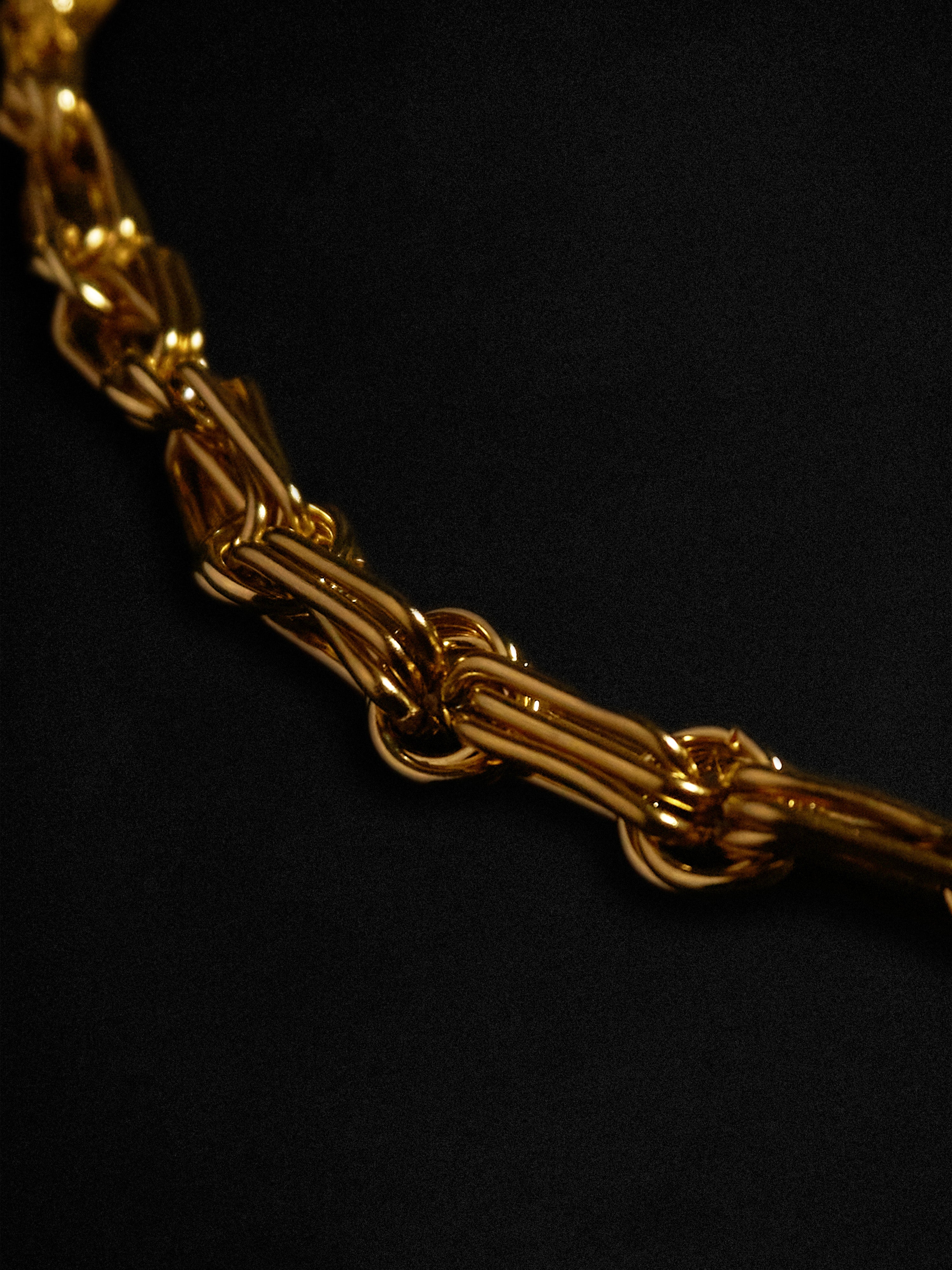 Close-up of a gold chain necklace on a black background