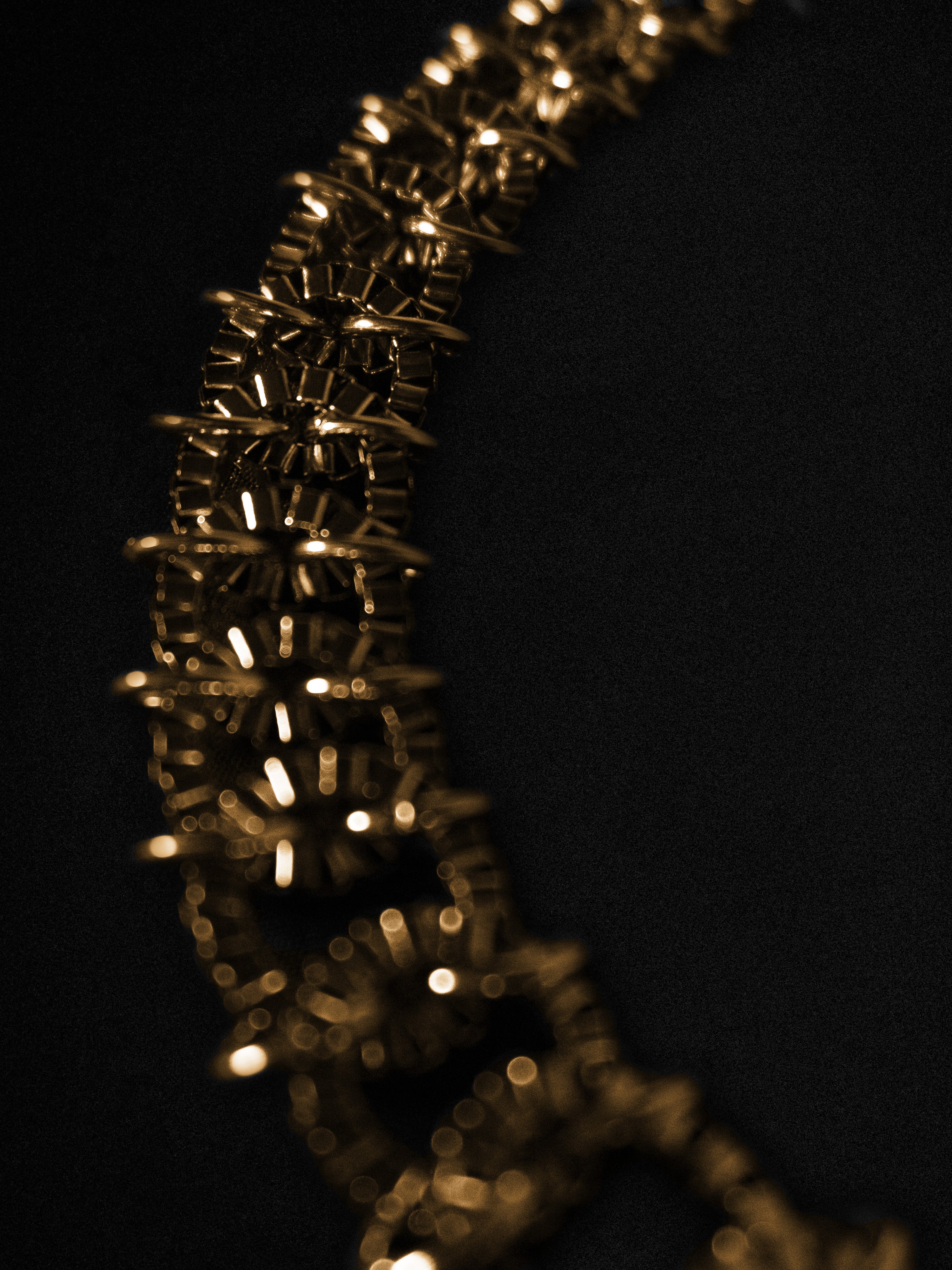 Close-up of a gold chain necklace on a black background