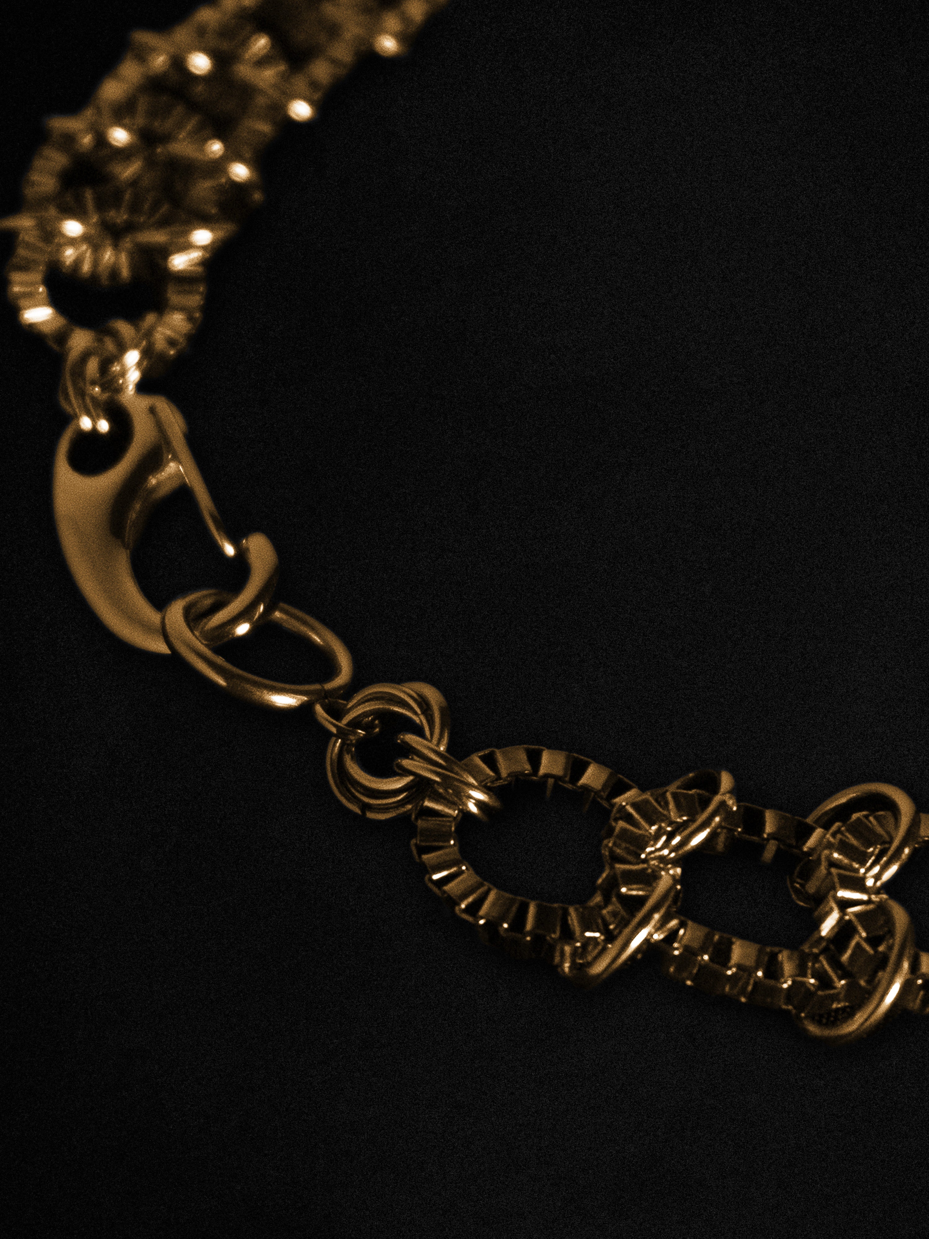Close up of a gold chain necklace on a black background