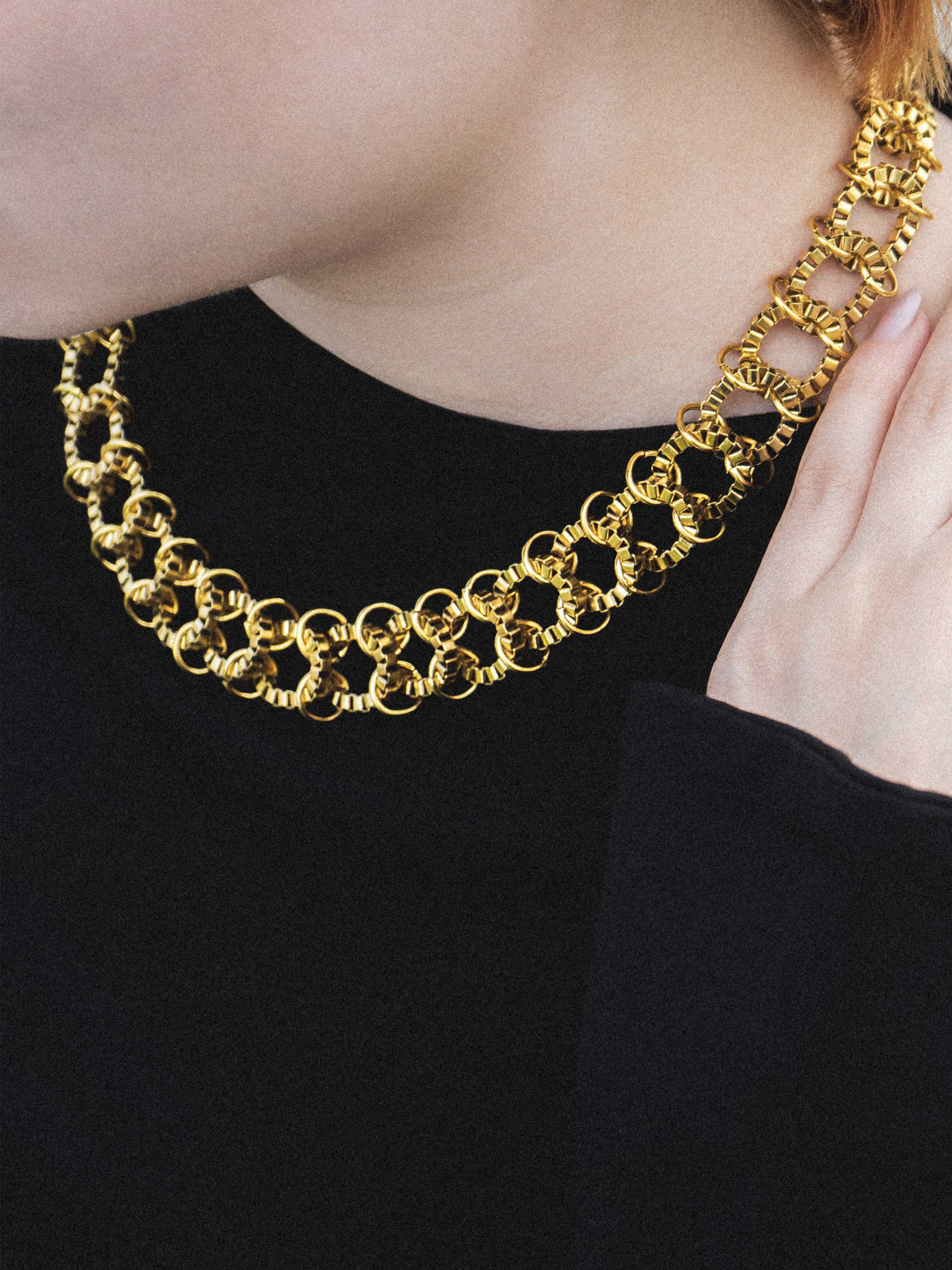 Gold chain necklace being worn by a person wearing a black top