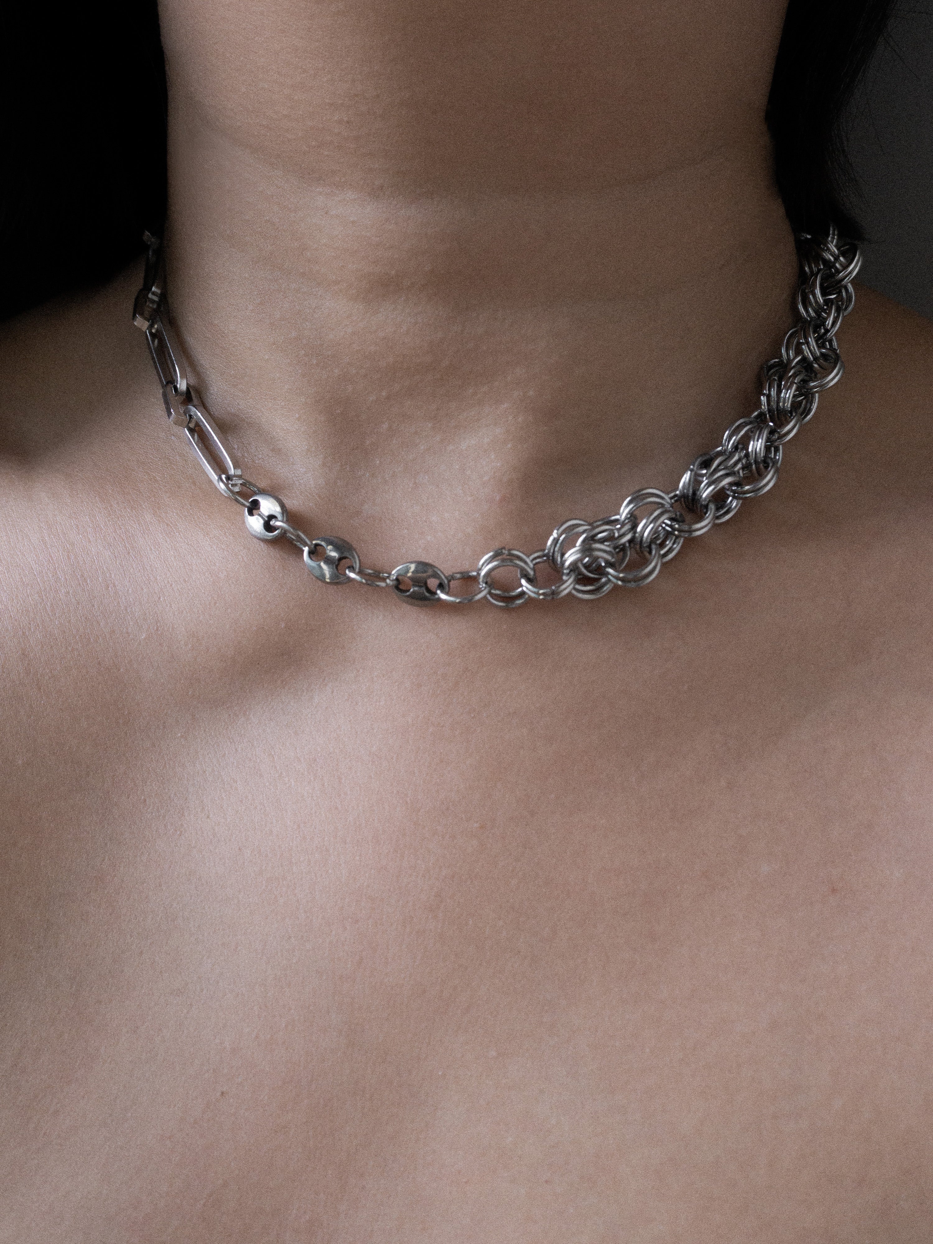Silver chain necklace on a person's neck against a dark background