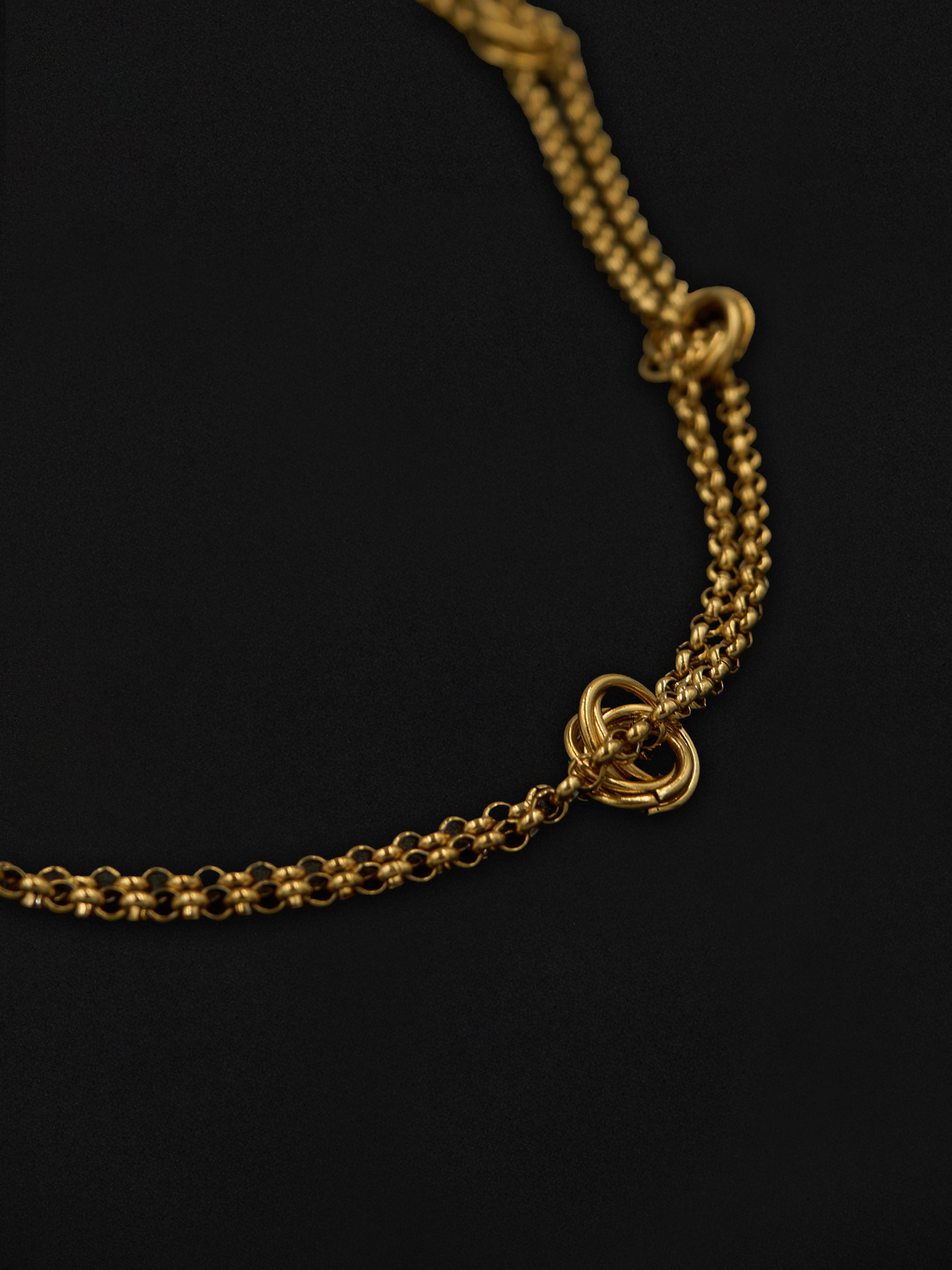 Close up of a gold chain necklace on a black background