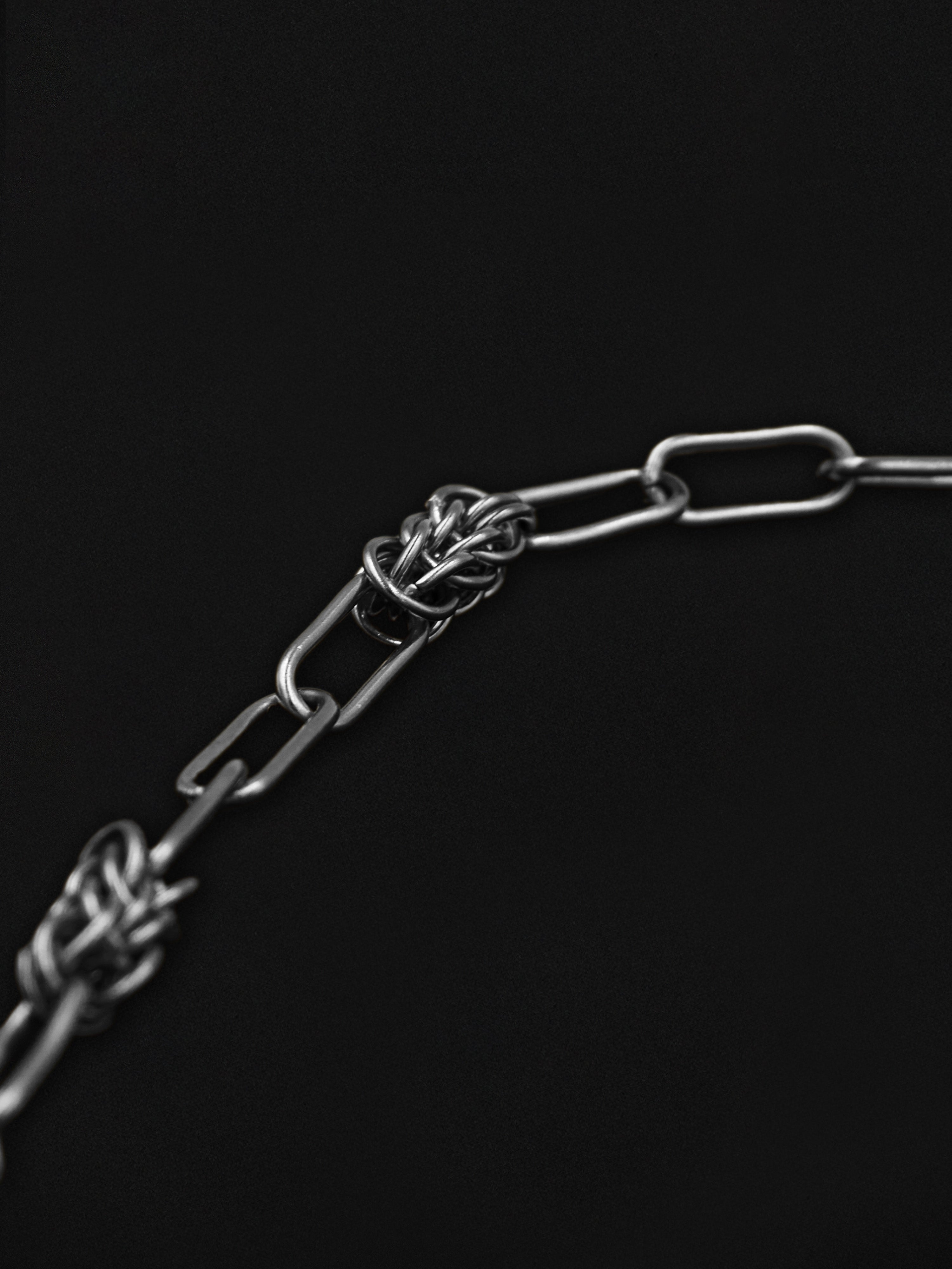 Metal chain with a knot on a black background