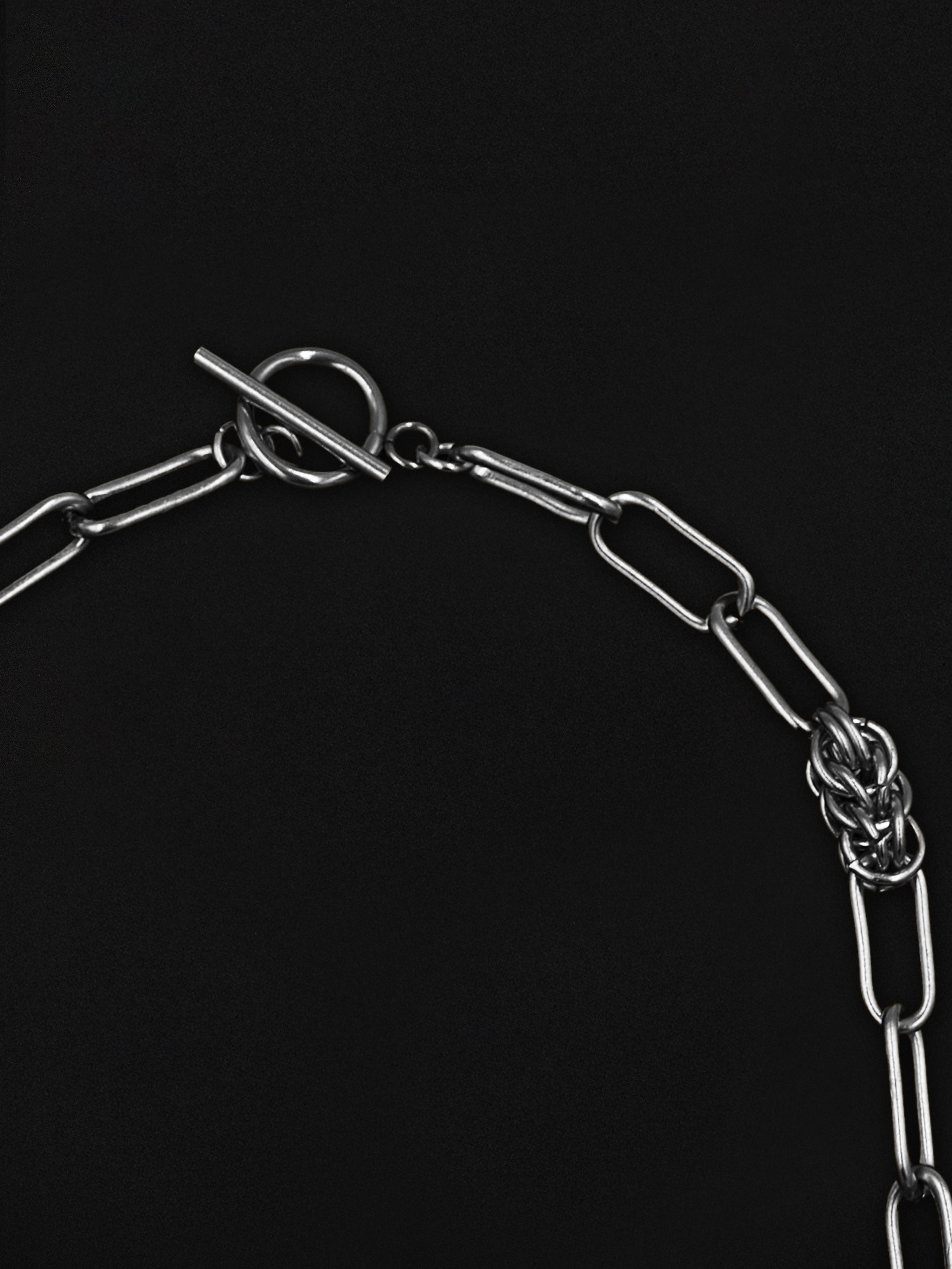 Close-up of a silver chain with a clasp on a black background