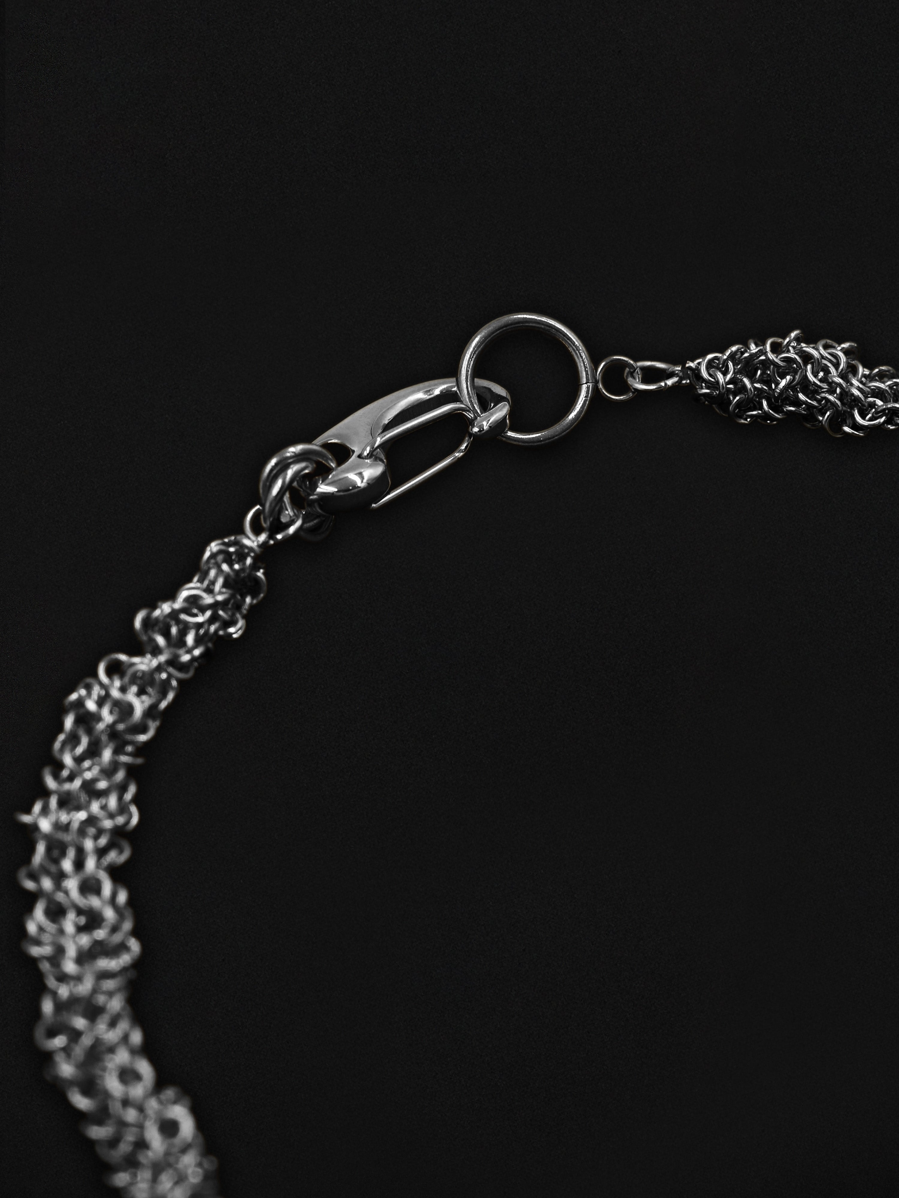 Close-up of a silver chain necklace on a black background