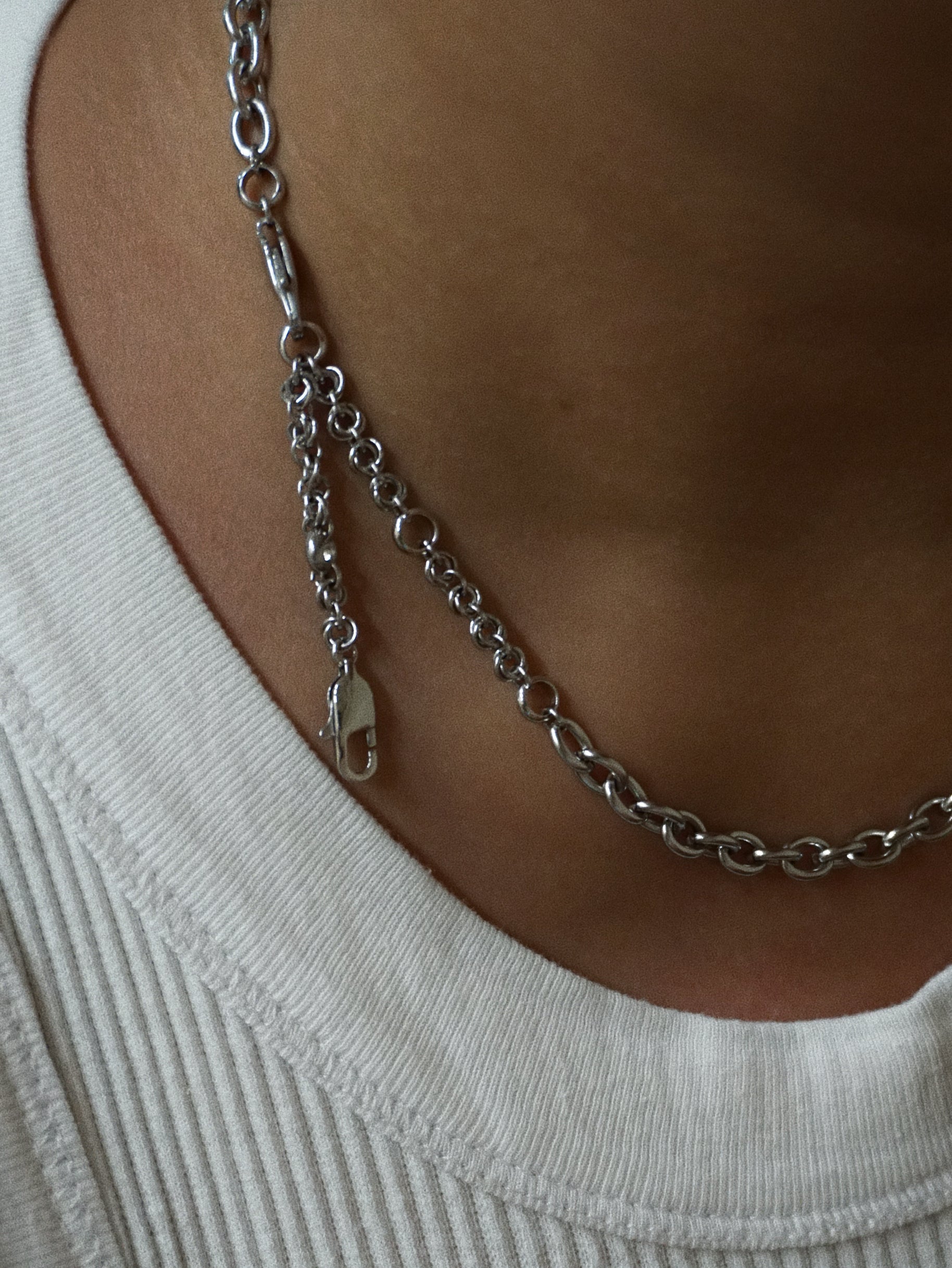 Silver chain necklace on a person wearing a white top