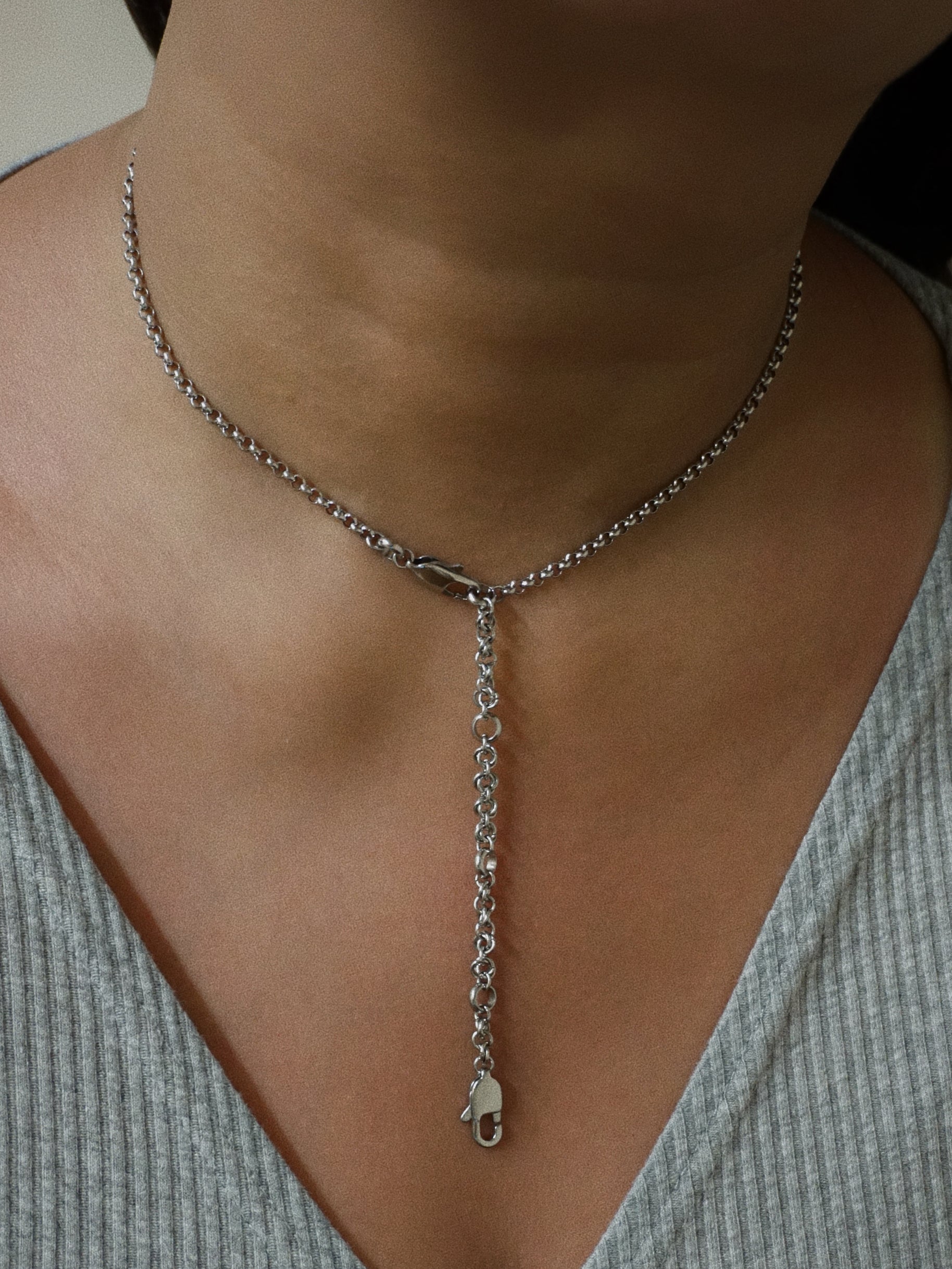 Silver chain necklace worn by a person with a neutral background