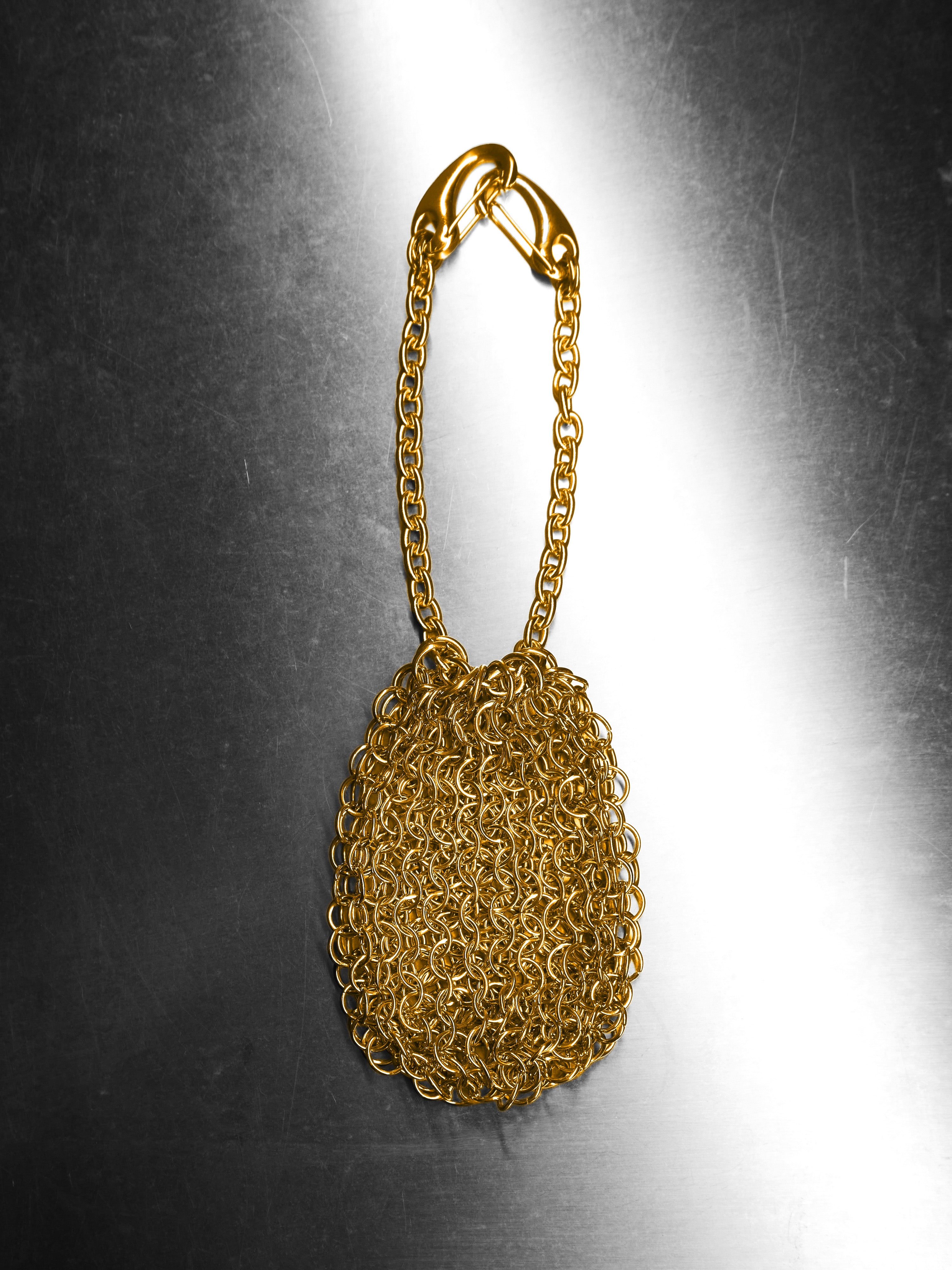 Gold chainmail bag on a reflective surface