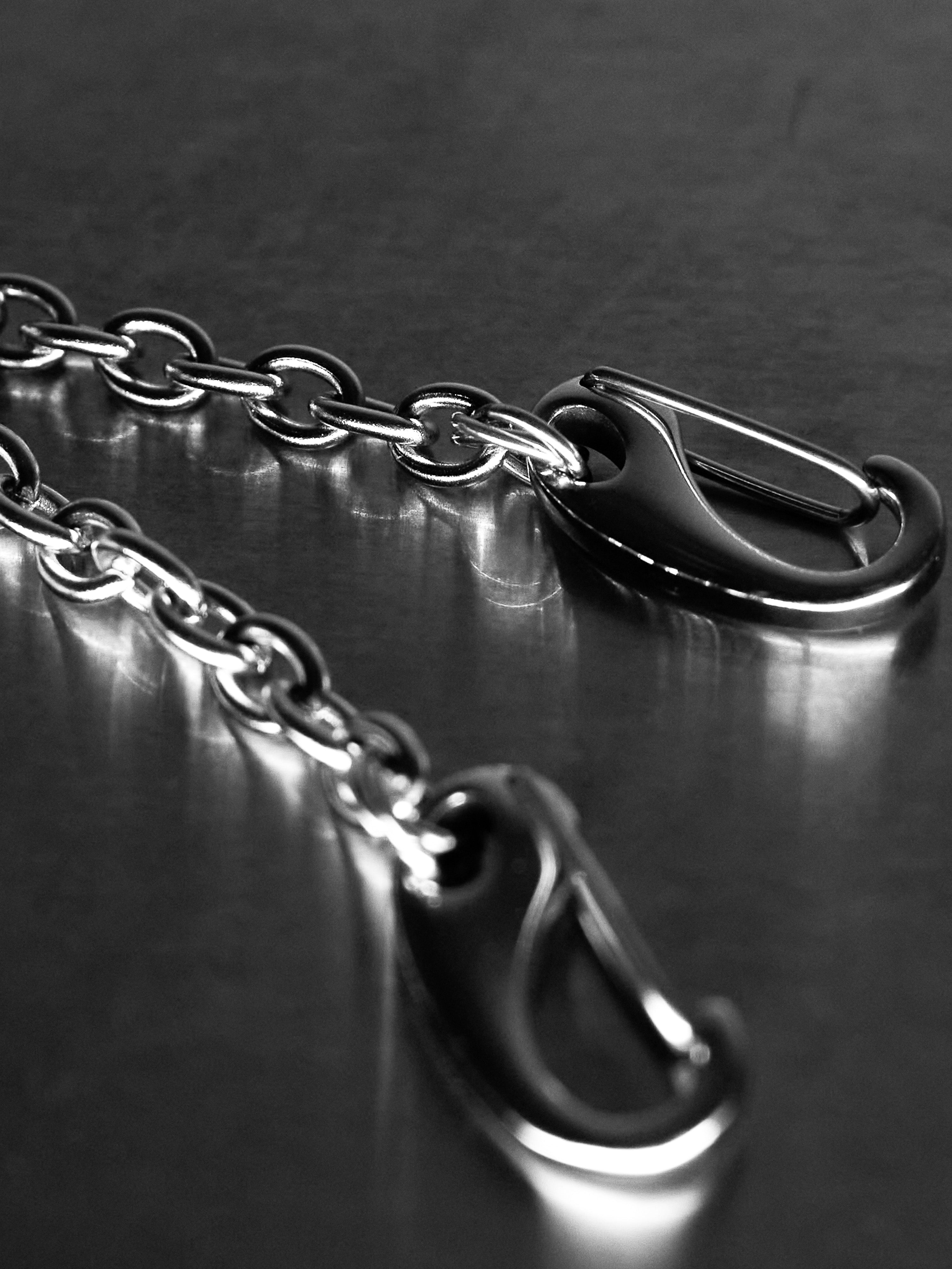 Close-up of a metal chain with clasp on a reflective surface