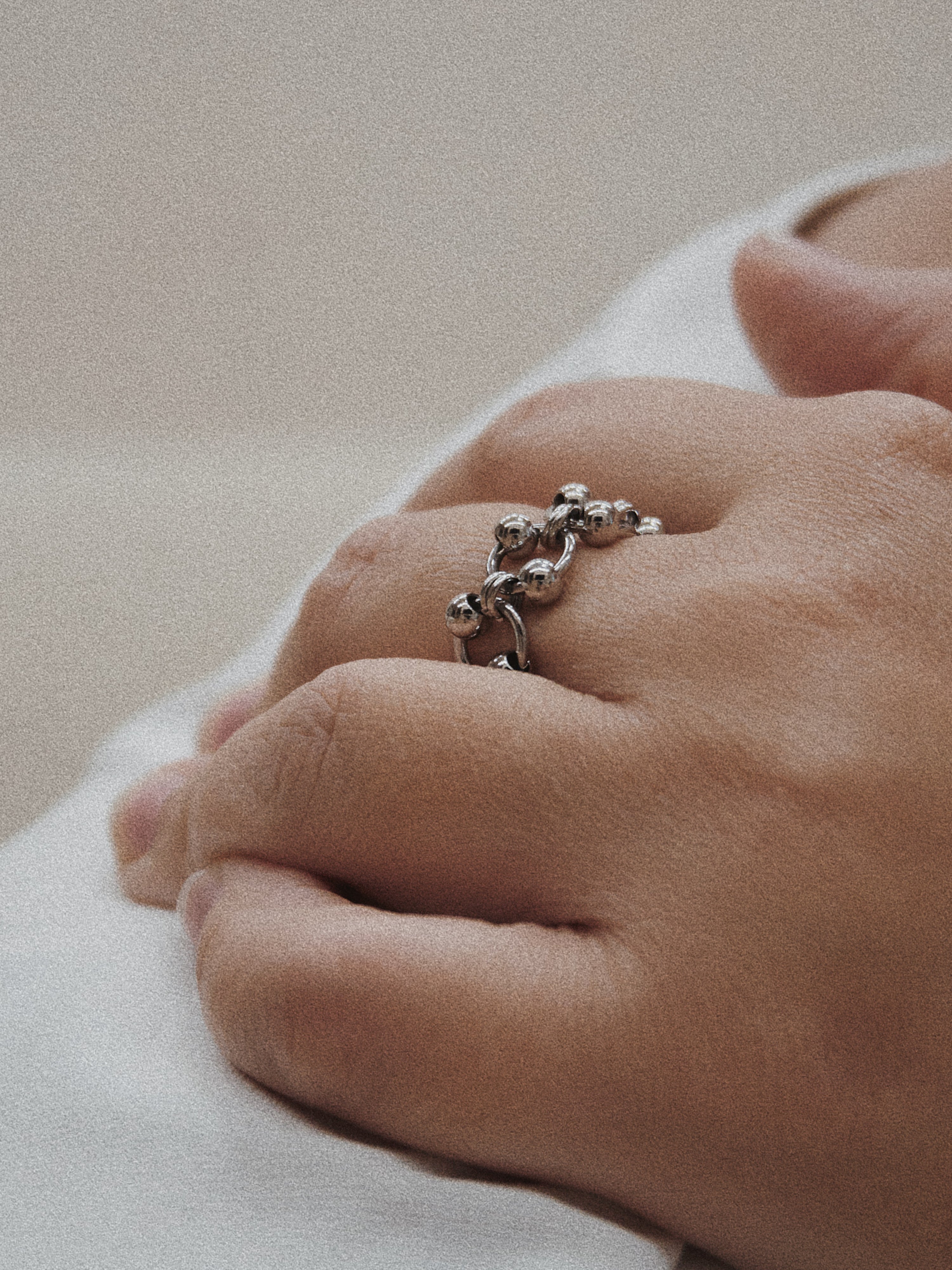 Close-up of a hand wearing a silver ring on a light background